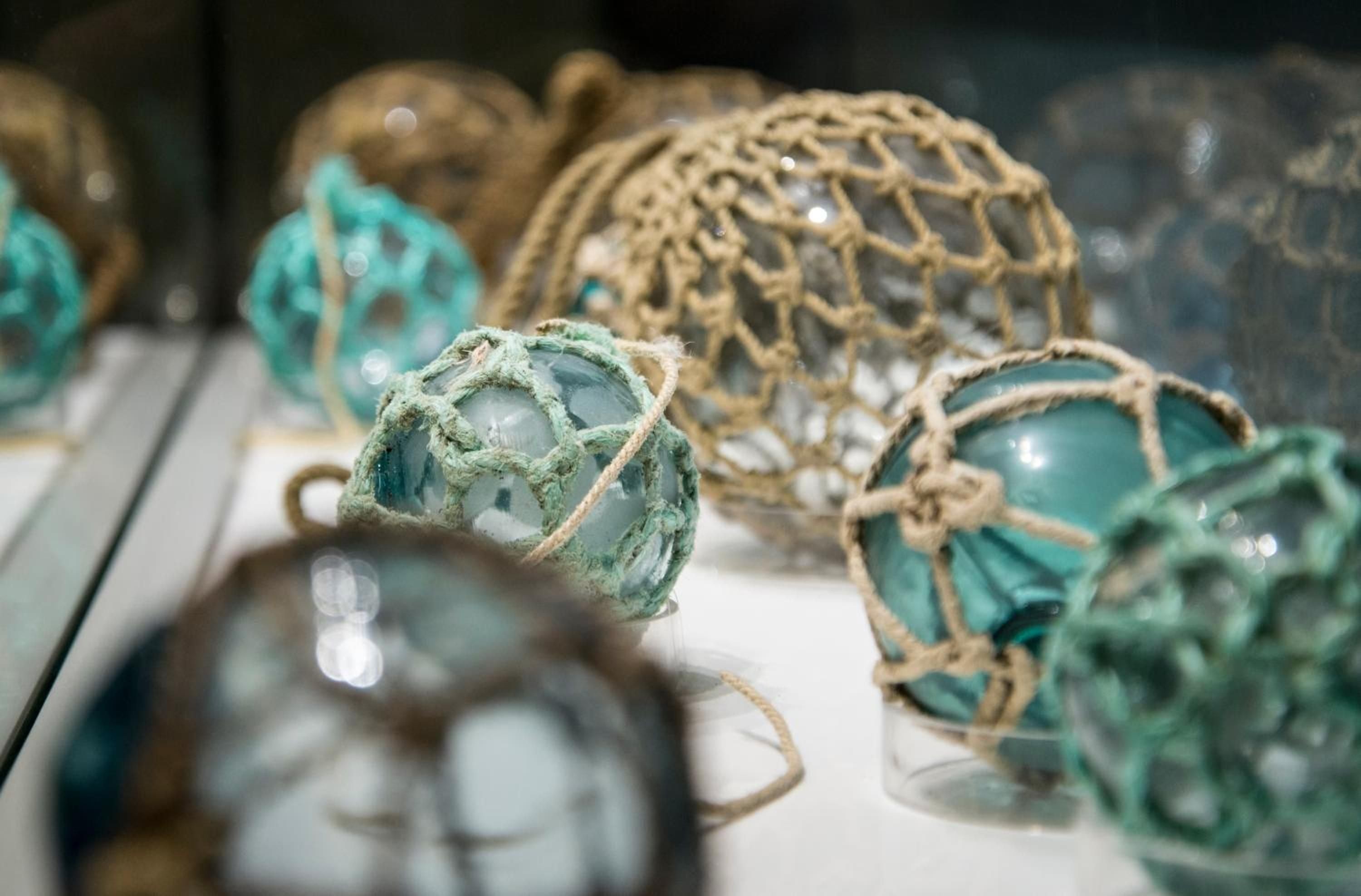 Weathered glass fishing floats wrapped in rope netting create coastal charm, their sea-green hues catching light like treasures washed ashore from Pacific waters.