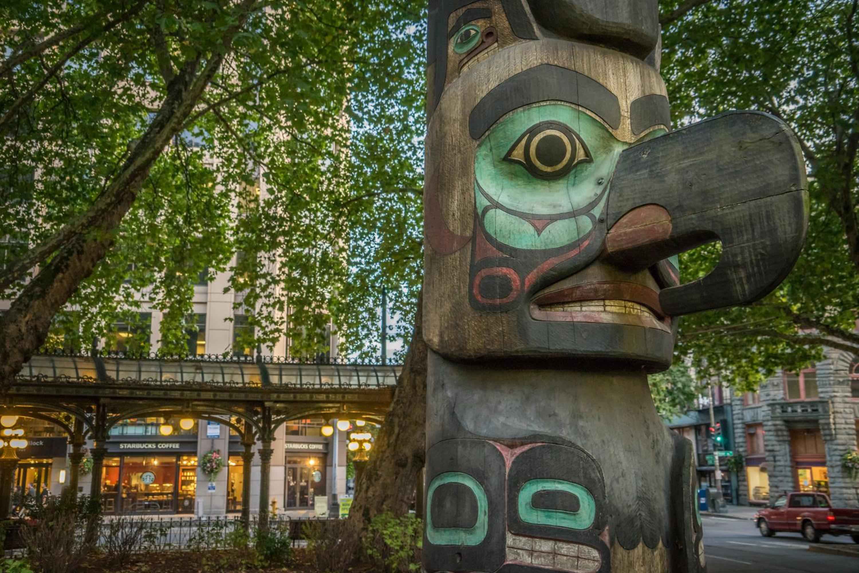 A towering Pacific Northwest totem pole stands sentinel outside the hotel, its weathered cedar and vibrant turquoise paint reflecting the region's rich indigenous heritage.