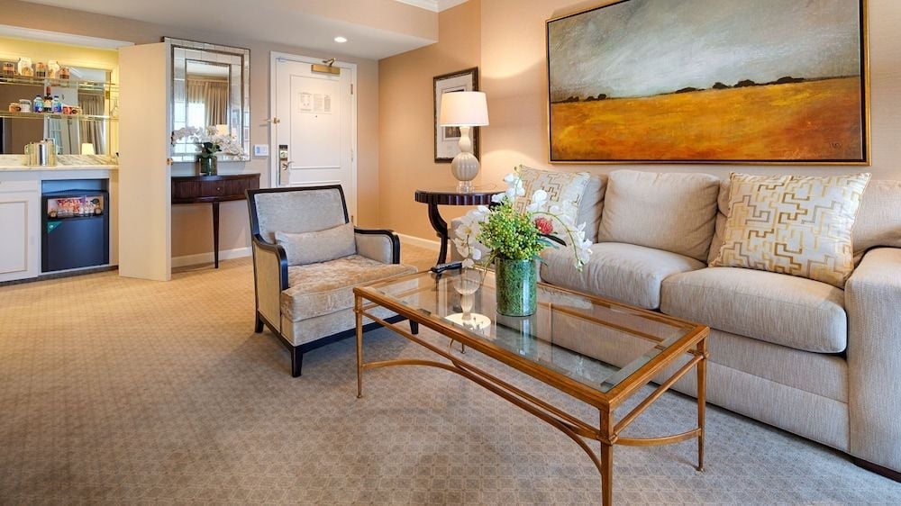 Warm amber walls and a golden landscape painting create an inviting atmosphere in this spacious suite, where glass and brass accents catch the soft lamplight.