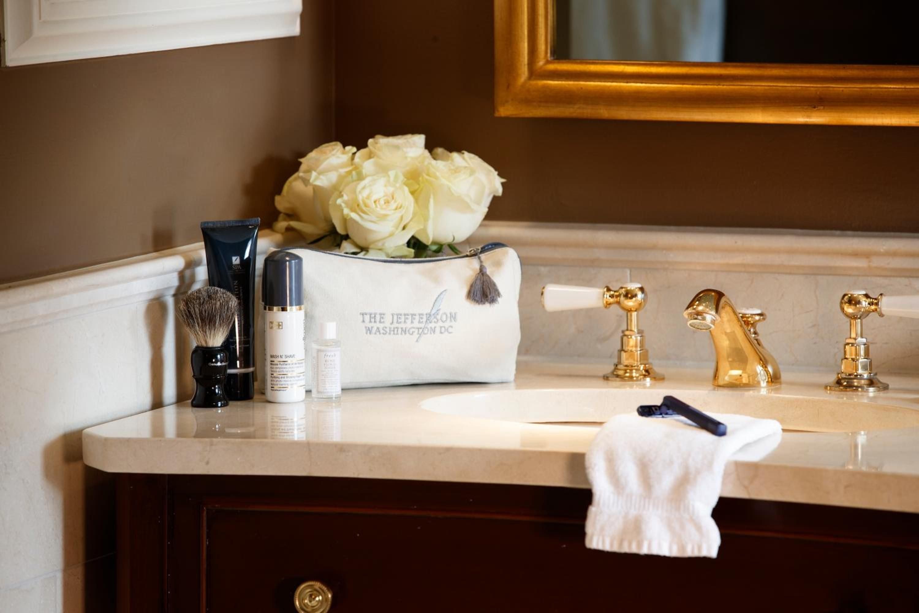 Gleaming brass fixtures and crisp white roses transform the marble vanity into a portrait of understated luxury, where classic elegance meets thoughtful amenities.