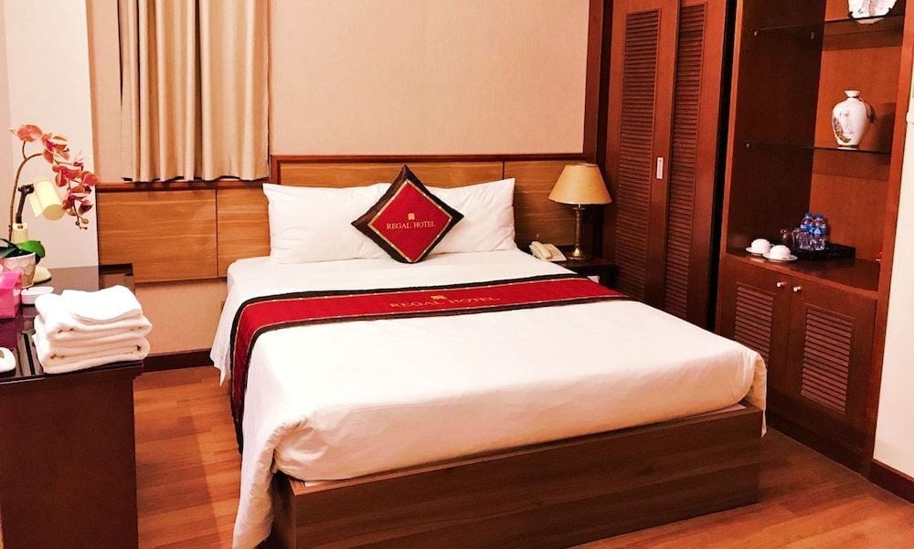 Warm wood tones and crisp white linens create an inviting sanctuary, where traditional Vietnamese touches meet contemporary comfort in this thoughtfully appointed guest room.