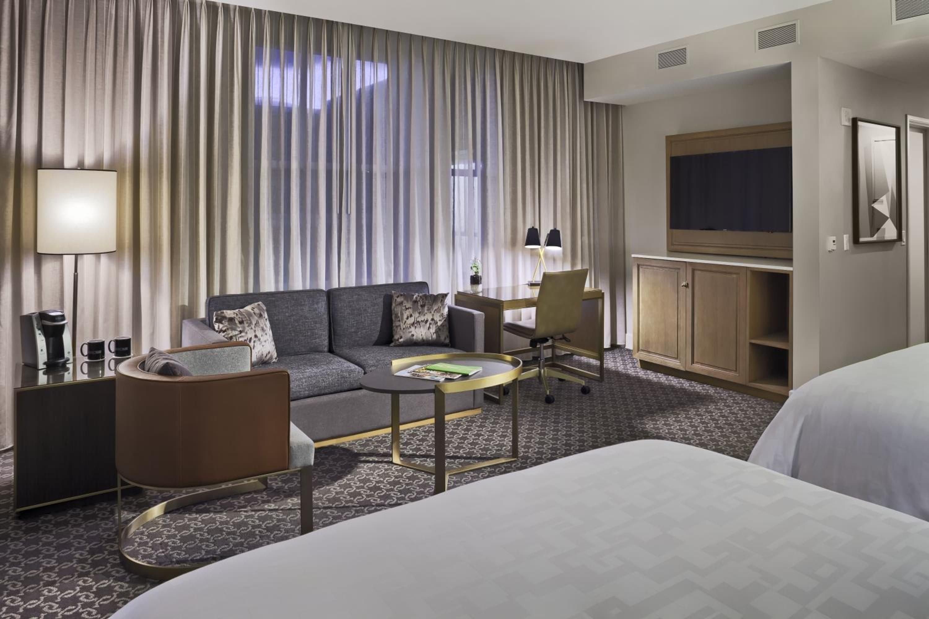 Sophisticated neutrals and rich textures define this spacious suite, where charcoal seating and geometric carpets create an urbane retreat steps from Denver's theater district.