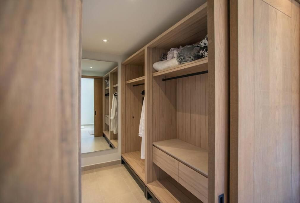 Custom-crafted wardrobes in warm blonde wood create a spa-like sanctuary, where natural light filters through this thoughtfully designed dressing area's clean lines and built-in storage.