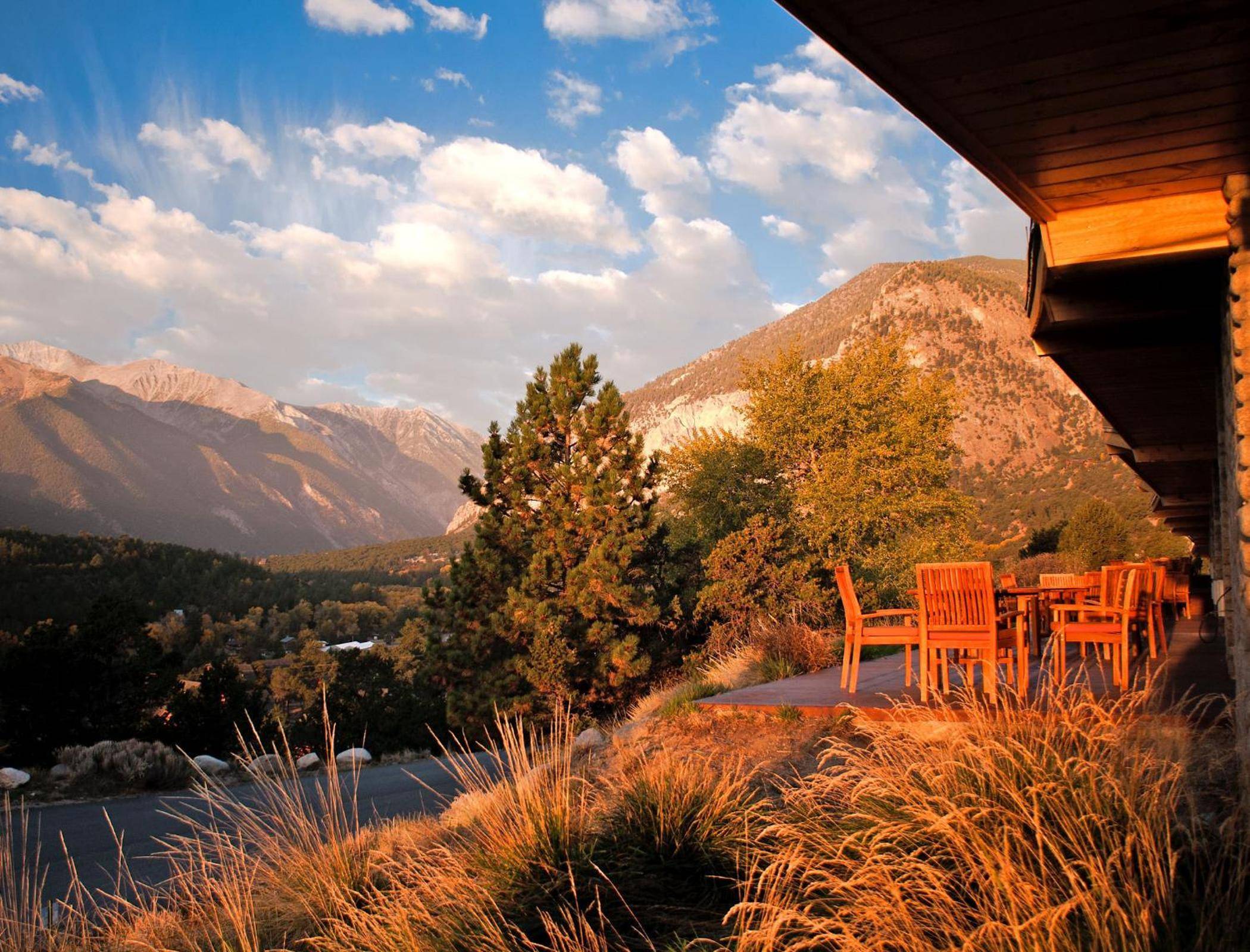 Golden hour bathes the resort's terrace in warm light, where Adirondack chairs frame sweeping views of Colorado's Collegiate Peaks and autumn-kissed foothills.