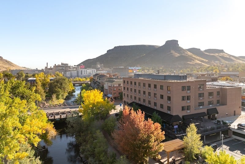 Golden autumn foliage frames the Truckee River as it winds through downtown, with the dramatic Castle Rock formation rising beyond the urban landscape.