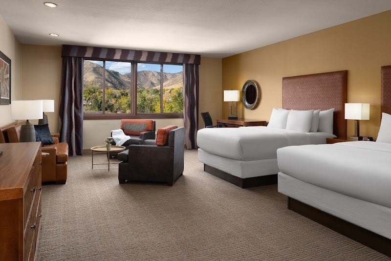 Mountain vistas frame this thoughtfully appointed guest room, where warm earth tones and crisp linens create a serene retreat after exploring Colorado's rugged landscape.