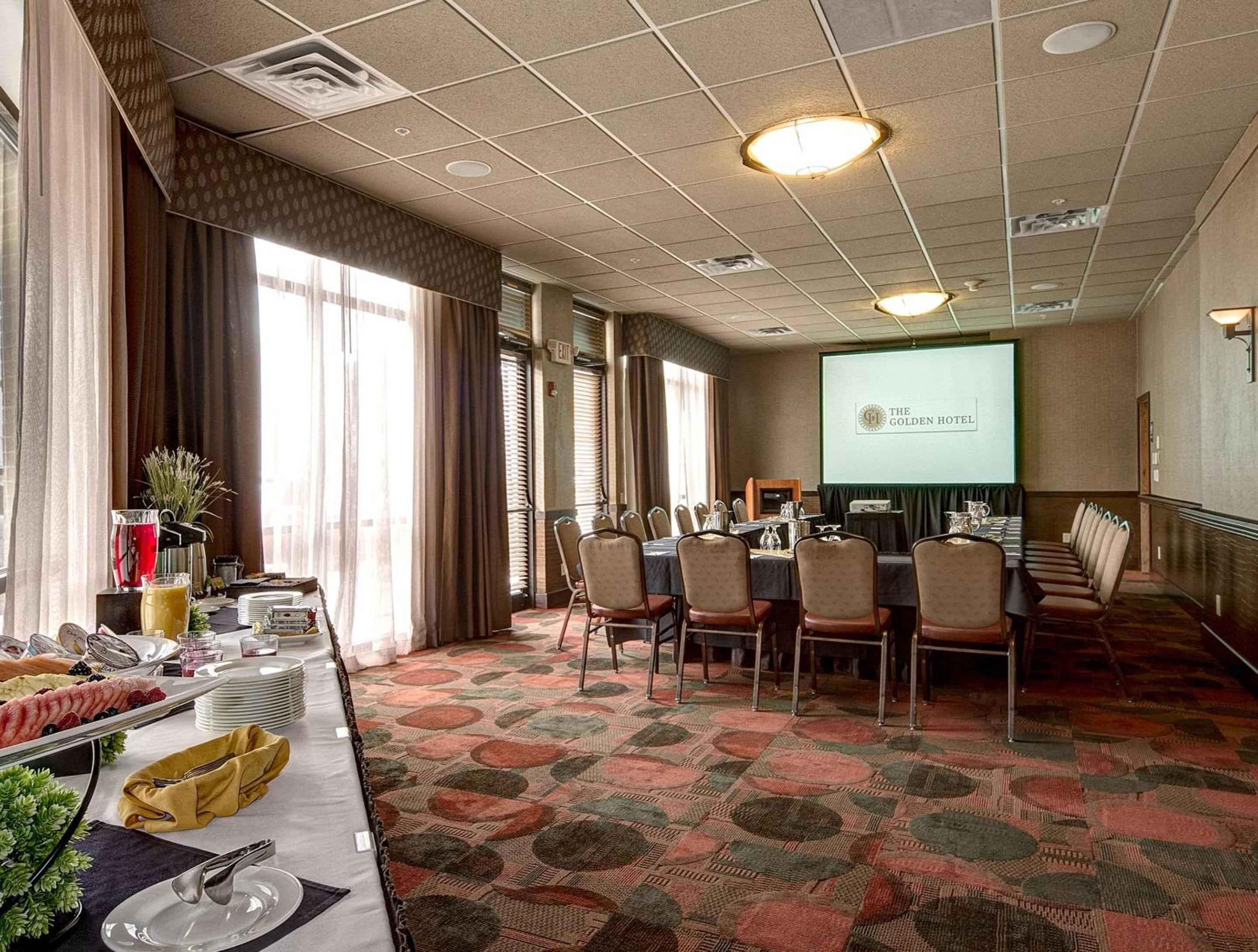 Warm earth tones and geometric carpeting create an inviting conference space where natural light streams through floor-to-ceiling windows overlooking the cityscape.
