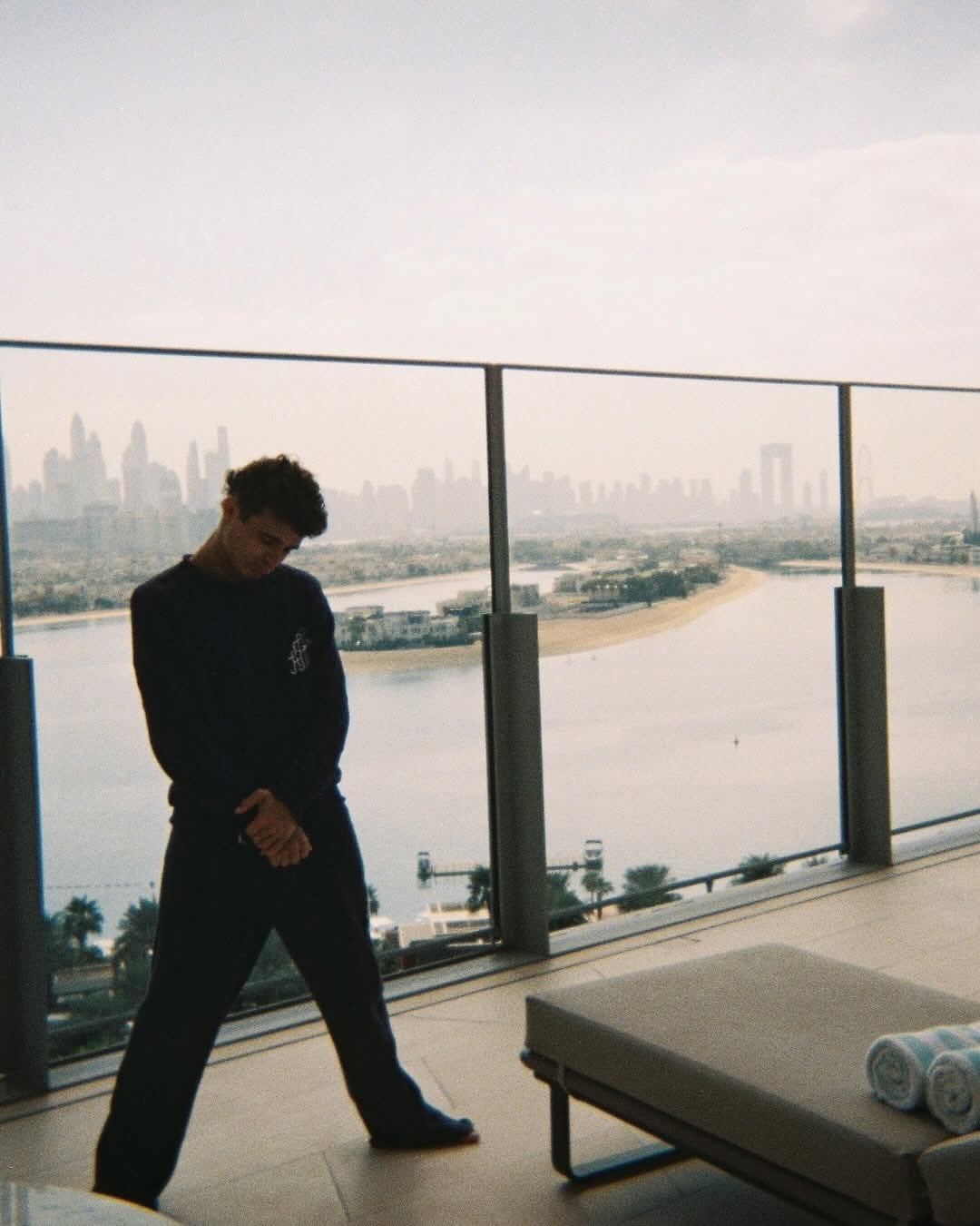 Floor-to-ceiling windows frame sweeping city vistas from the minimalist living space, where concrete and glass create a serene backdrop for contemplating the urban landscape below.