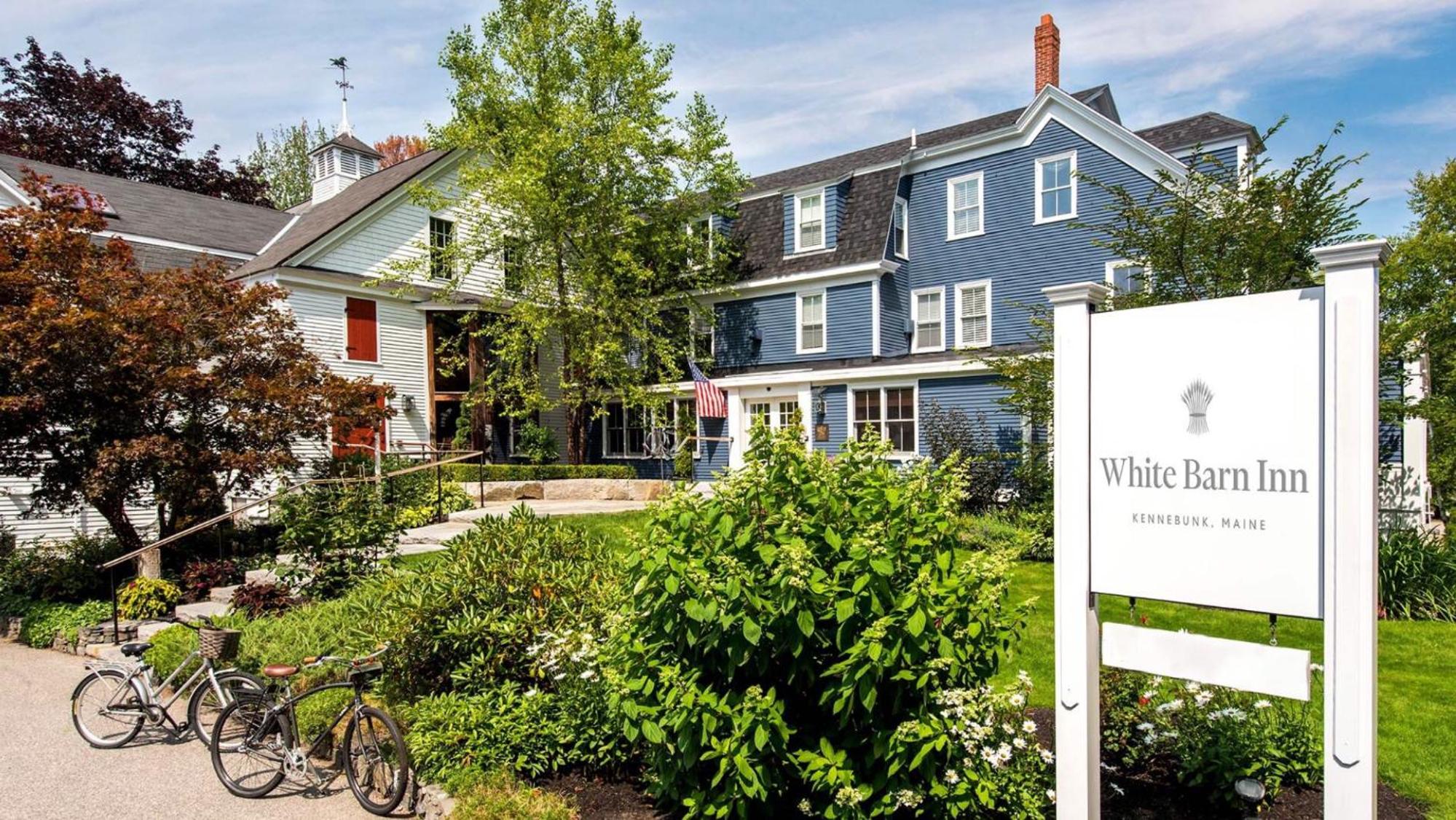 Classic New England charm radiates from the inn's blue clapboard facade, where bicycles await coastal adventures and manicured gardens frame this Kennebunk retreat.