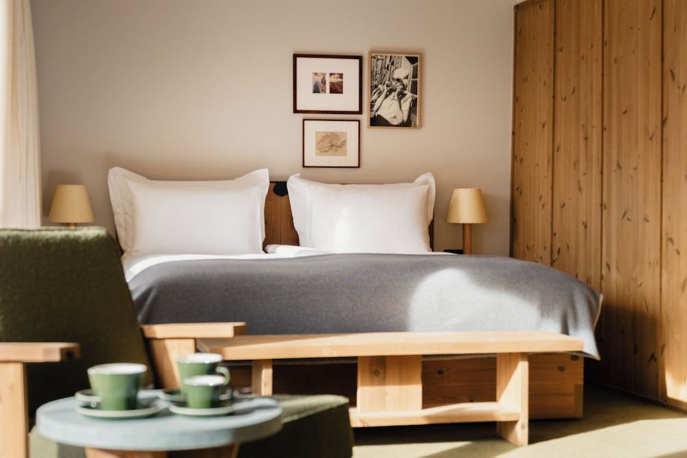 Warm wood paneling and crisp white linens create a serene alpine retreat, where morning coffee feels like a ritual in this thoughtfully appointed guest room.