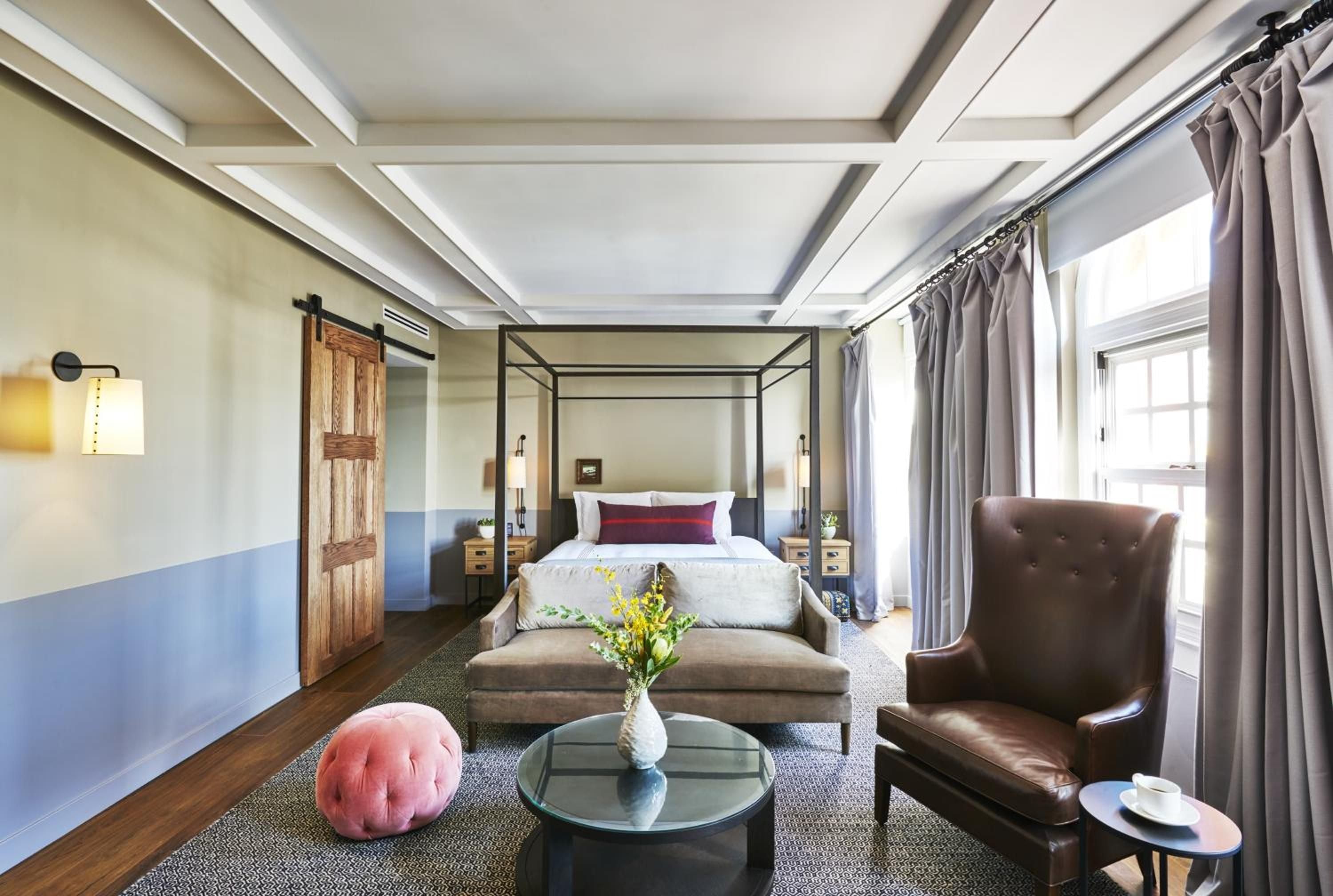 Coffered ceilings and a striking blue-painted wainscot frame this sophisticated suite, where a canopy bed anchors the sleeping area beyond a chic seating lounge.