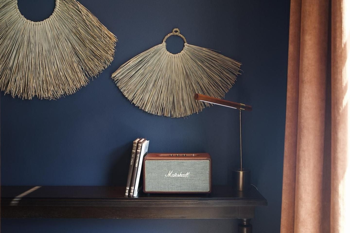 Natural textures meet navy sophistication in thoughtfully curated guest rooms, where woven grass art, vintage Marshall speakers, and brass task lighting create an elevated mountain retreat aesthetic.