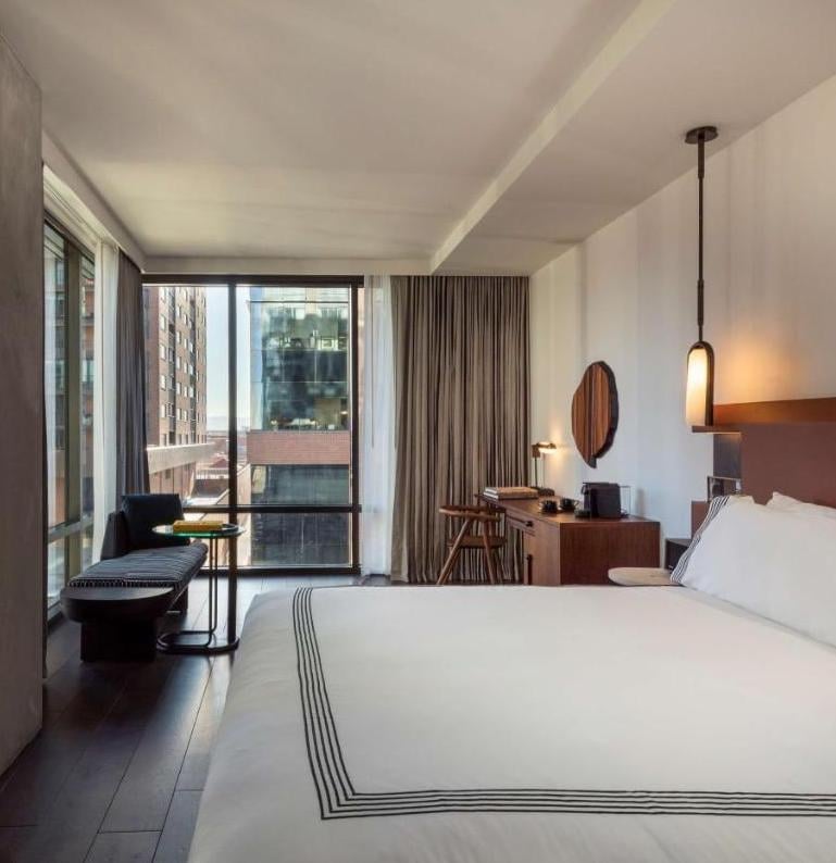 Floor-to-ceiling windows frame Denver's urban skyline while rich walnut furnishings and crisp white linens create a sophisticated sanctuary above the city streets.