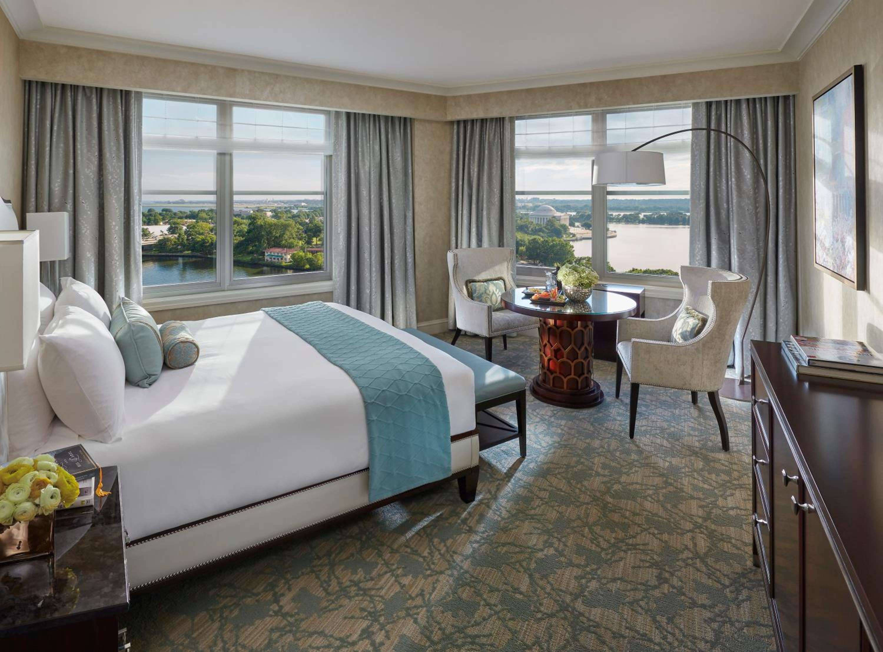Corner windows frame the Potomac River from this elegantly appointed suite, where teal accents and plush seating create an inviting retreat above Washington's waterfront.