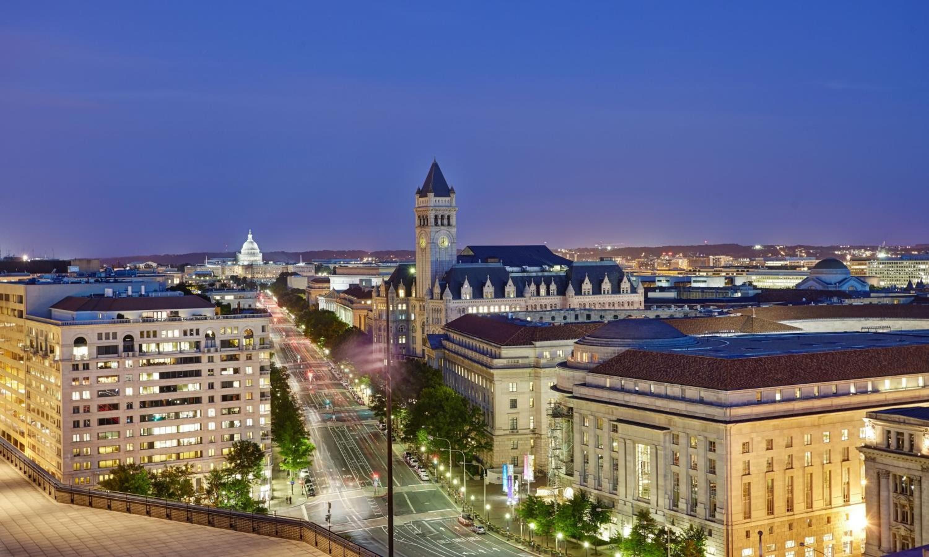 Pennsylvania Avenue stretches toward the illuminated Capitol dome from this commanding perch, where historic architecture meets the pulsing heart of political Washington at twilight.