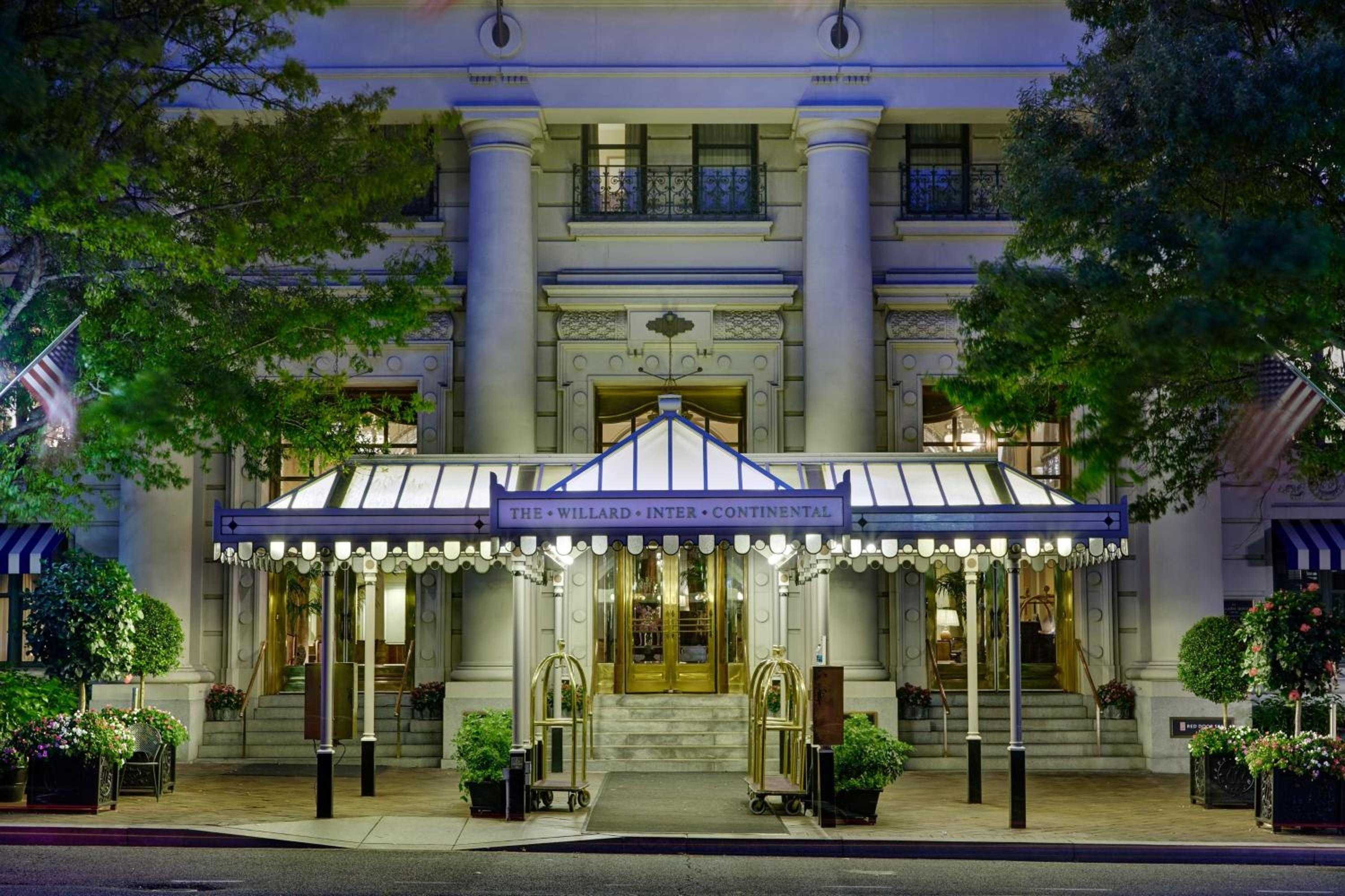 Stately columns and gleaming brass doors welcome guests beneath the elegant canopy, where classic Beaux-Arts grandeur meets timeless Washington sophistication at twilight.