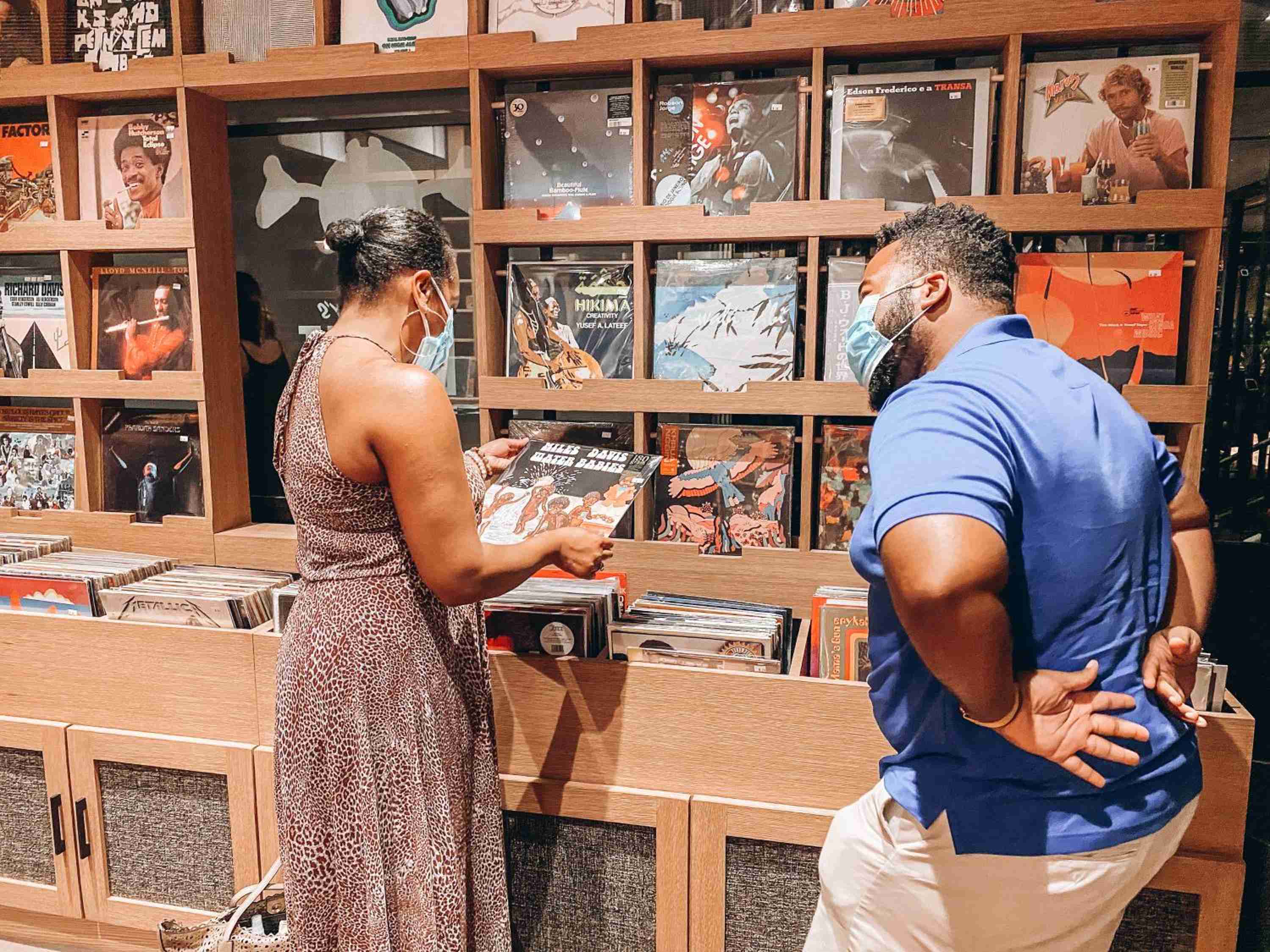 Vinyl enthusiasts browse carefully curated records in the hotel's intimate music corner, where wooden shelving displays jazz legends and contemporary artists beneath warm ambient lighting.