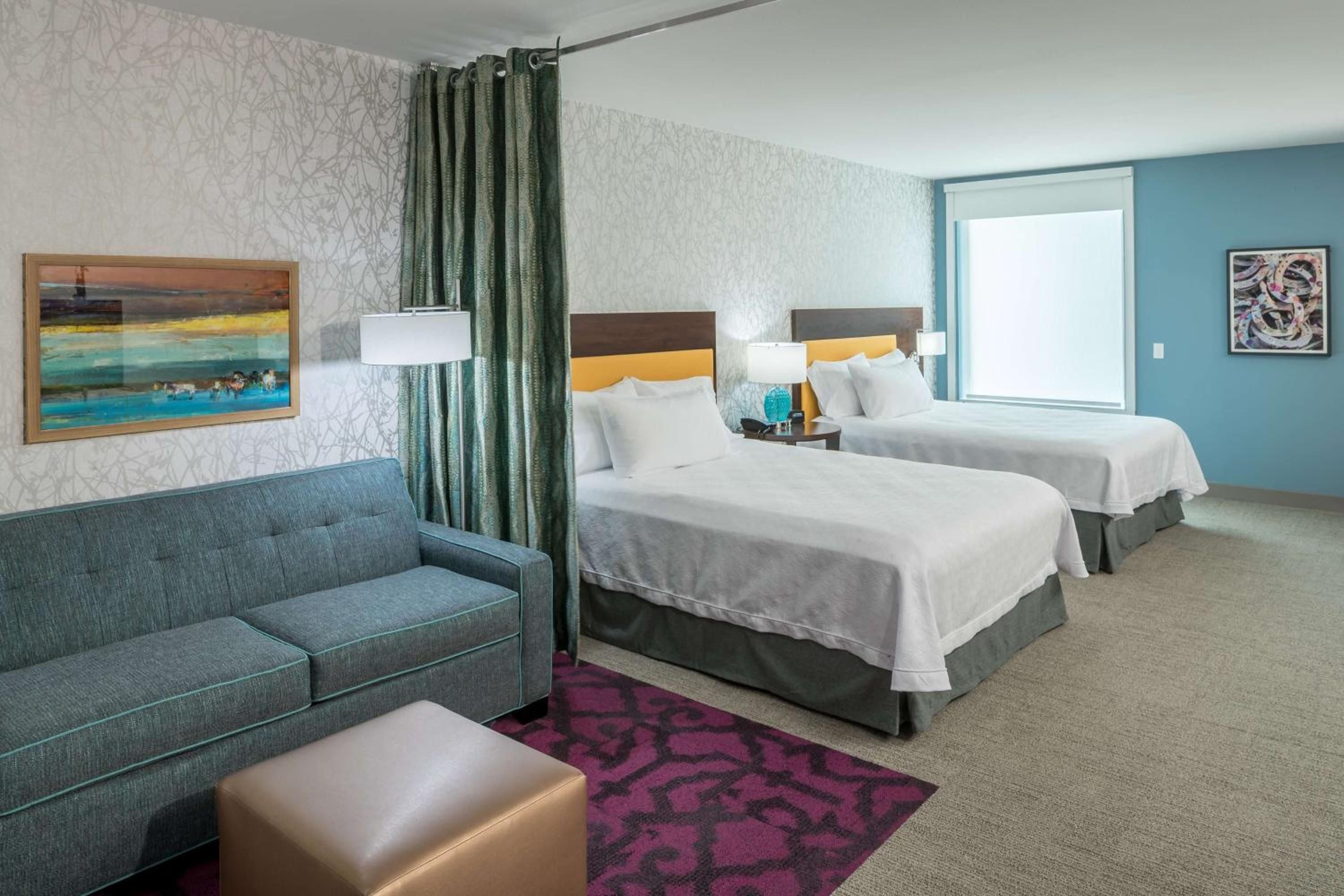 Seafoam blues and forest greens create a calming palette in this thoughtfully designed double queen suite, where contemporary furnishings meet coastal-inspired artwork and plush textures.