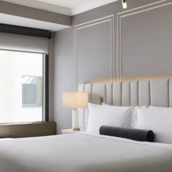 Crisp white linens meet sophisticated gray paneling in thoughtfully appointed guest rooms, where warm lamplight and clean lines create an understated urban sanctuary.