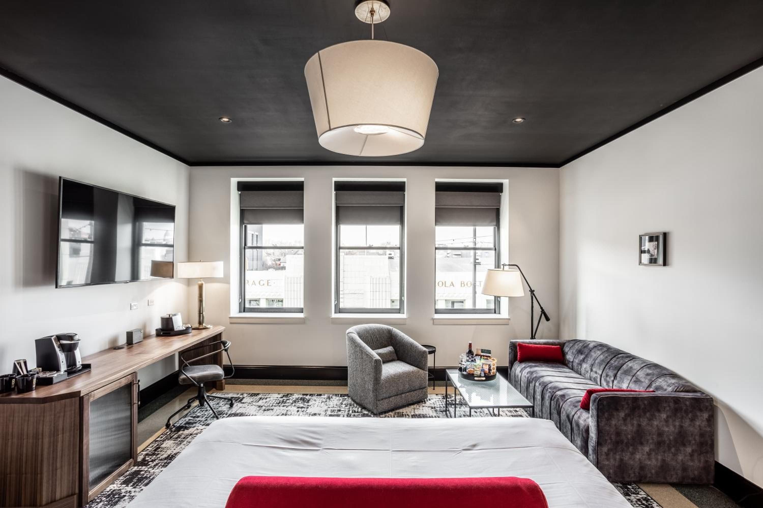 Charcoal ceilings create intimate contrast against cream walls in this thoughtfully appointed suite, where plaid upholstery and walnut desk details add warmth to modern urban sophistication.
