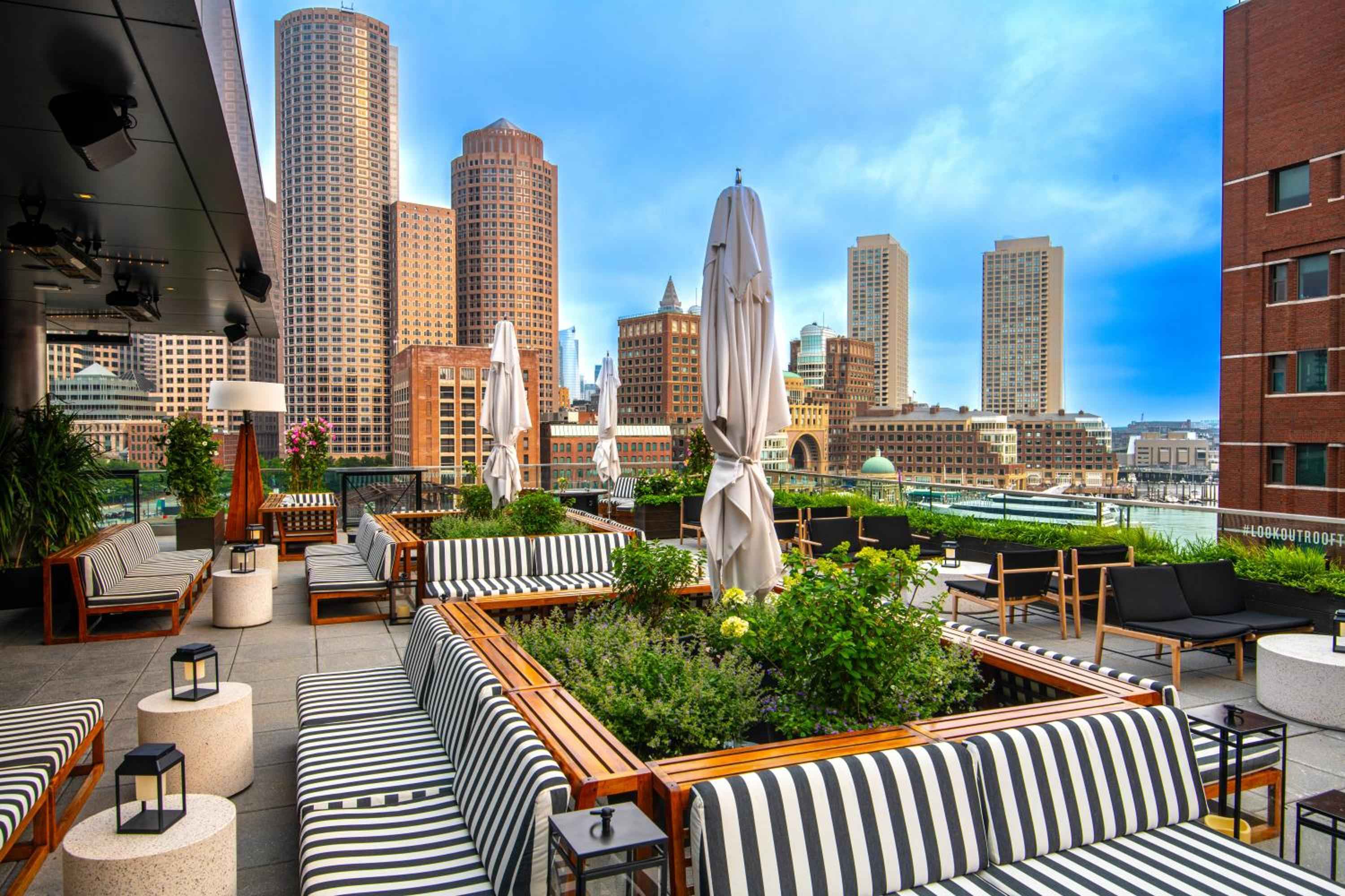 Striped cushions and planters brimming with herbs create an urban oasis above Boston's Financial District, where harbor breezes mingle with craft cocktails at sunset.