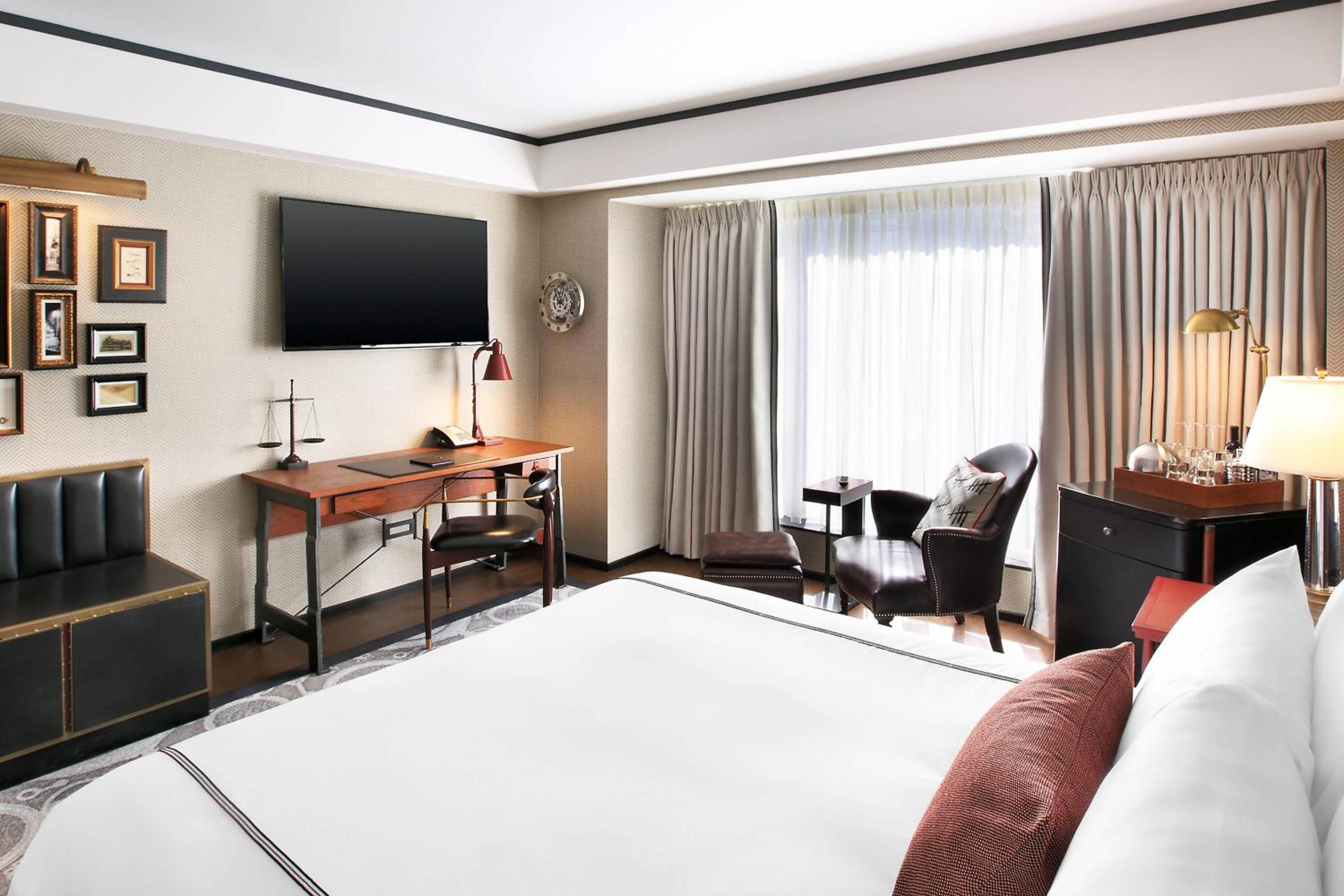 Warm wood tones and brass accents create an inviting workspace where natural light filters through tailored drapes, blending contemporary comfort with classic sophistication.