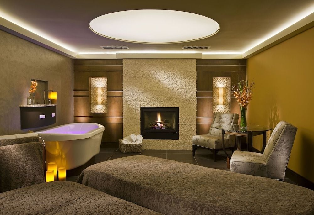 Candlelit fireplace and soaking tub with purple ambient lighting create an intimate sanctuary where mountain luxury meets sophisticated wellness design.