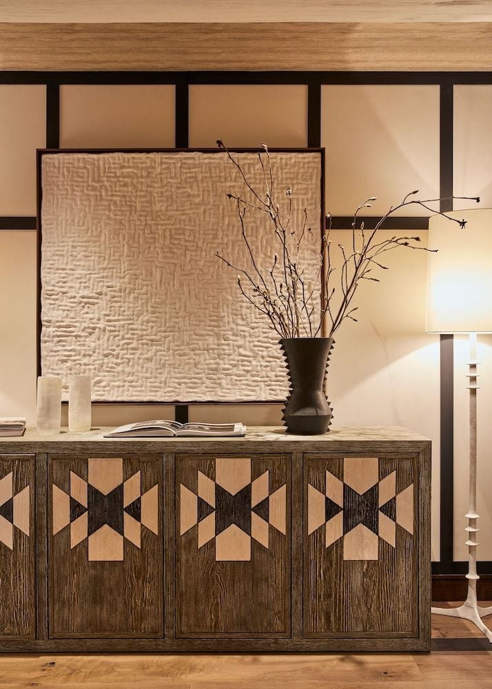 Hand-carved geometric patterns dance across rich walnut cabinetry while delicate branches catch golden light, creating an intimate moment of mountain lodge sophistication.