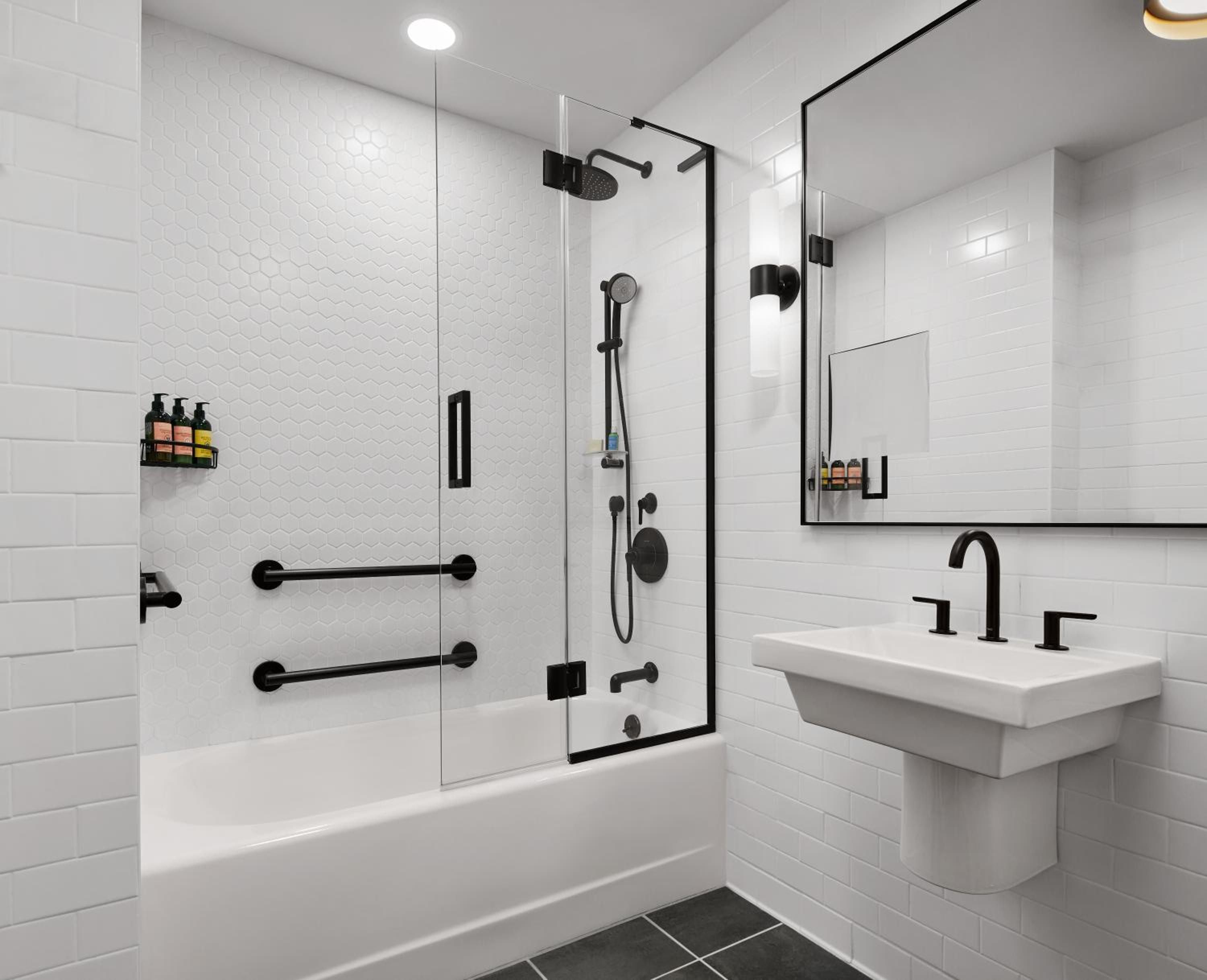 Sleek white subway tiles and matte black fixtures create a spa-like sanctuary, where rainfall showers and geometric patterns elevate the everyday ritual of bathing.