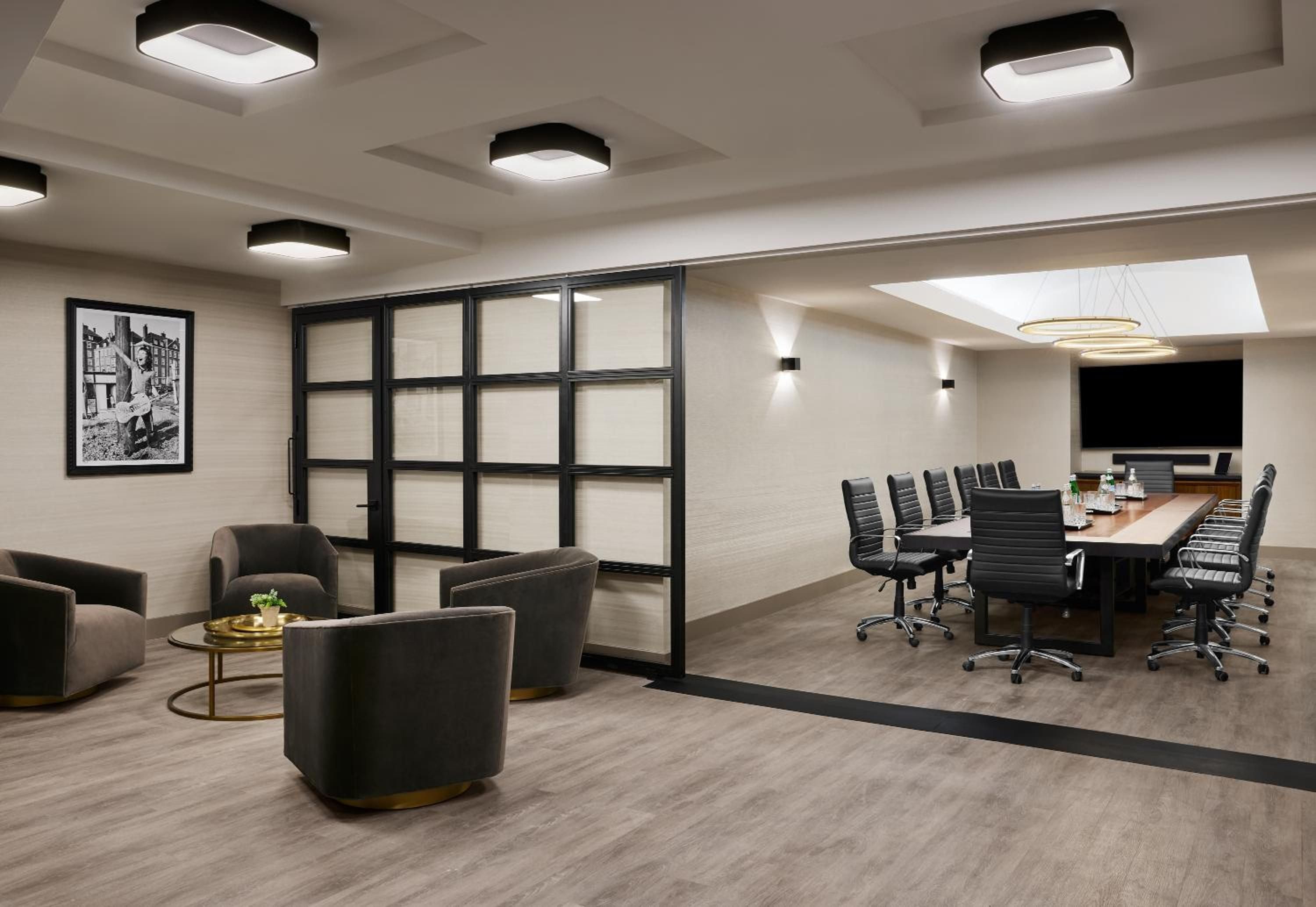 Floor-to-ceiling windows and sleek black fixtures define this executive boardroom, where polished wood tables and leather chairs create an atmosphere of sophisticated urban professionalism.