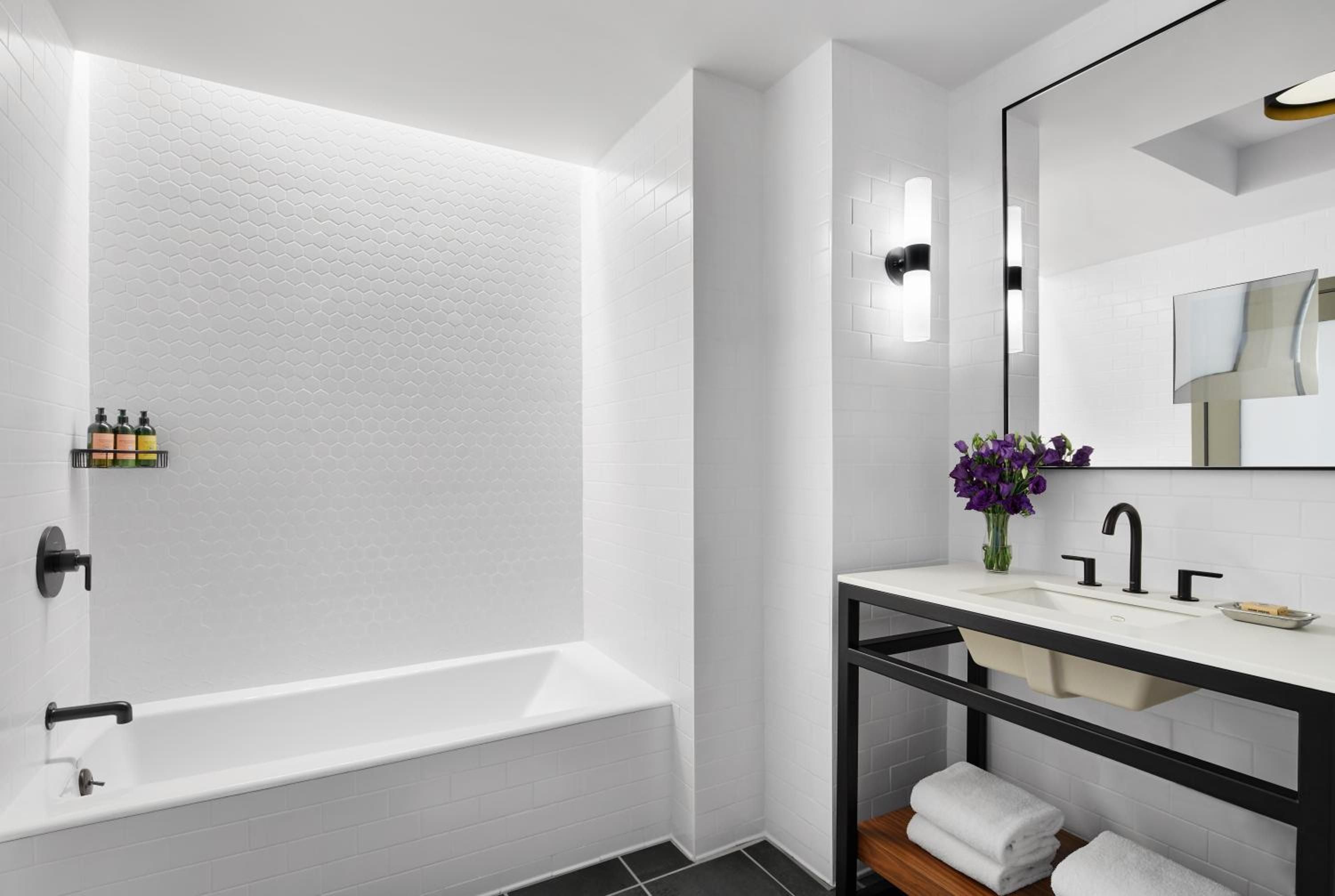 Crisp white hexagonal tiles and matte black fixtures create a striking monochrome palette in this sleekly appointed guest bathroom, where industrial-chic meets urban sophistication.