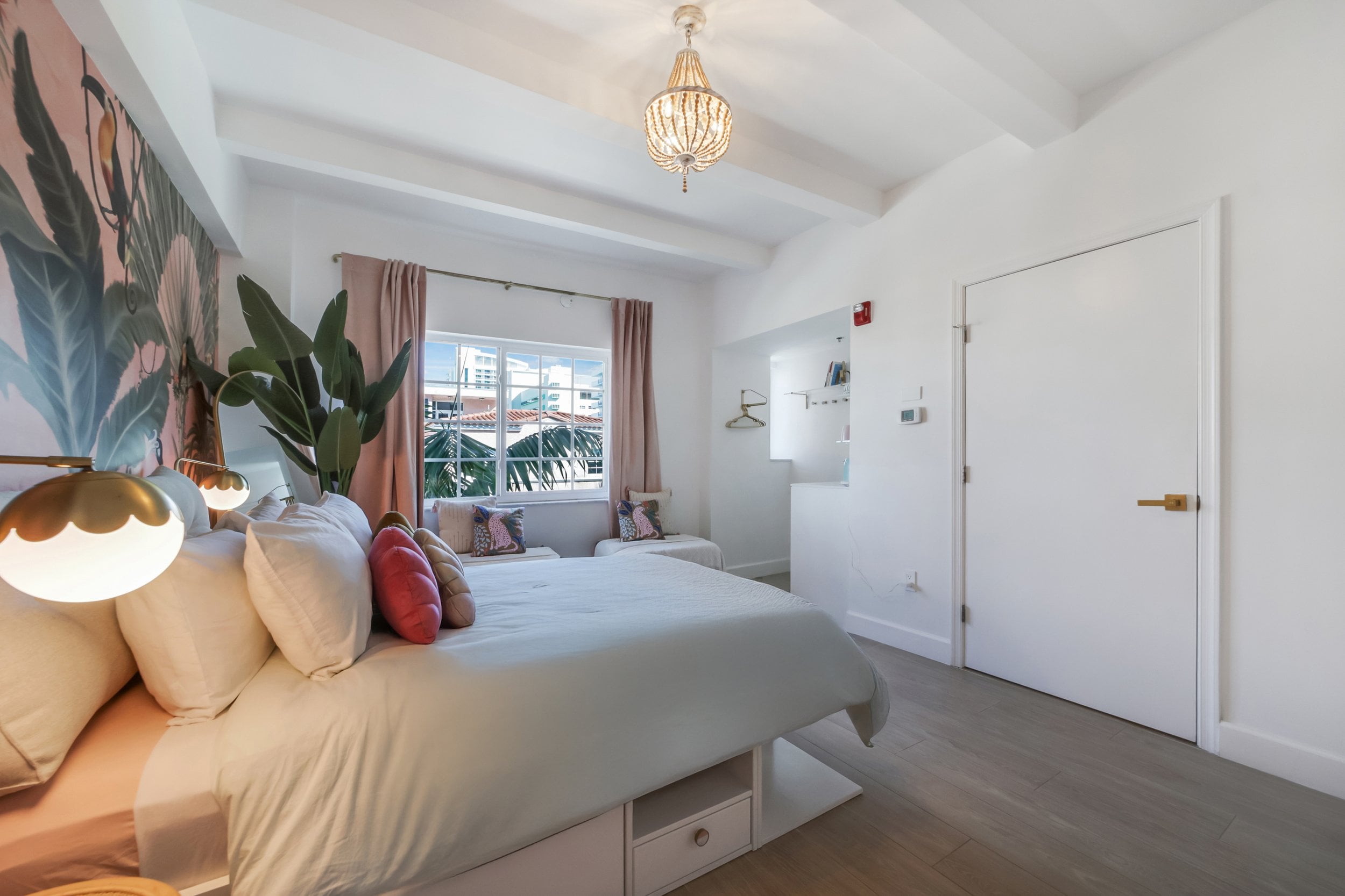 Tropical wallpaper and exposed white beams create an airy retreat, while the built-in bed platform maximizes space in this thoughtfully designed suite.