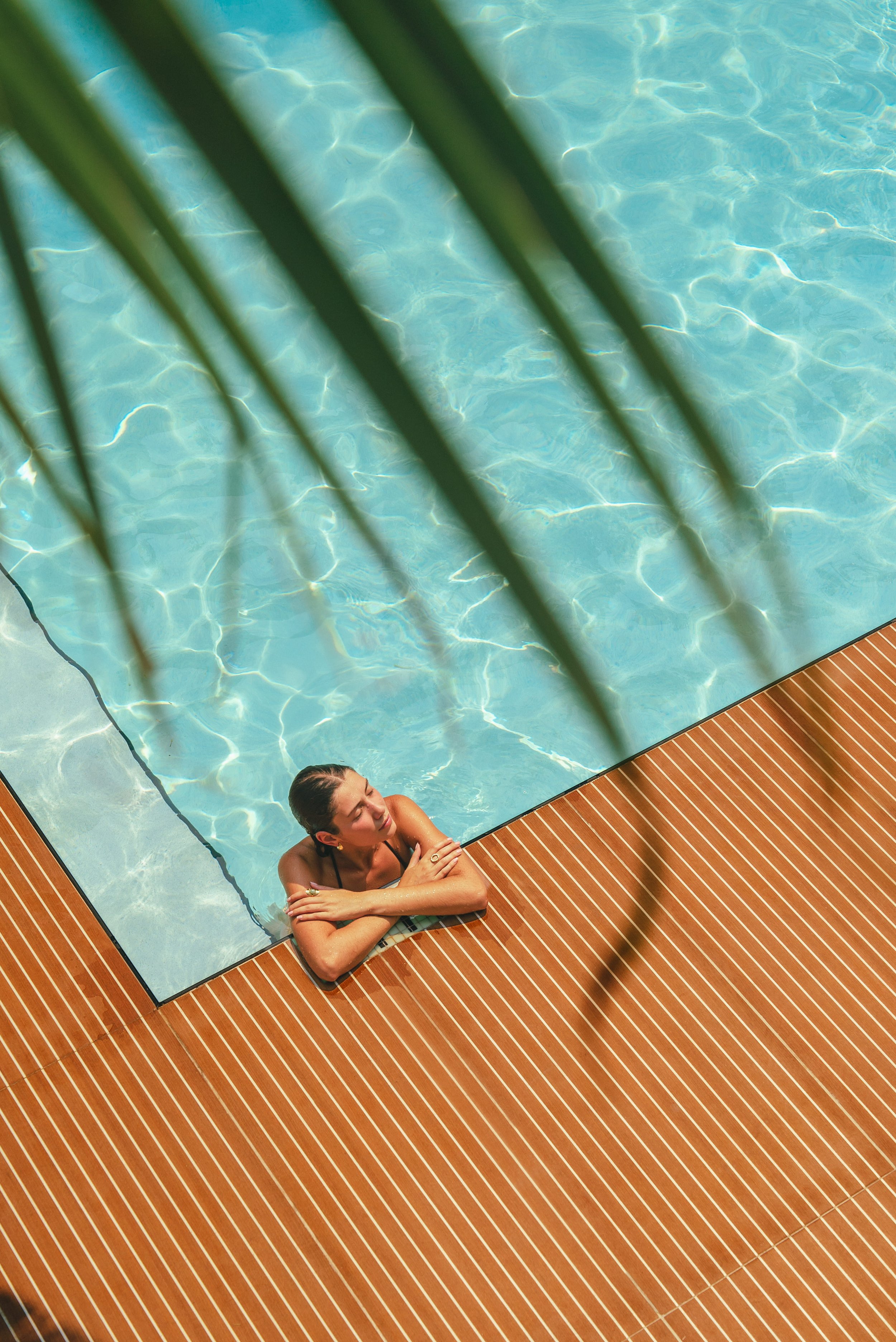 Crystalline water ripples catch afternoon light as shadows from nearby palms dance across the infinity pool's edge at this intimate Mediterranean retreat.
