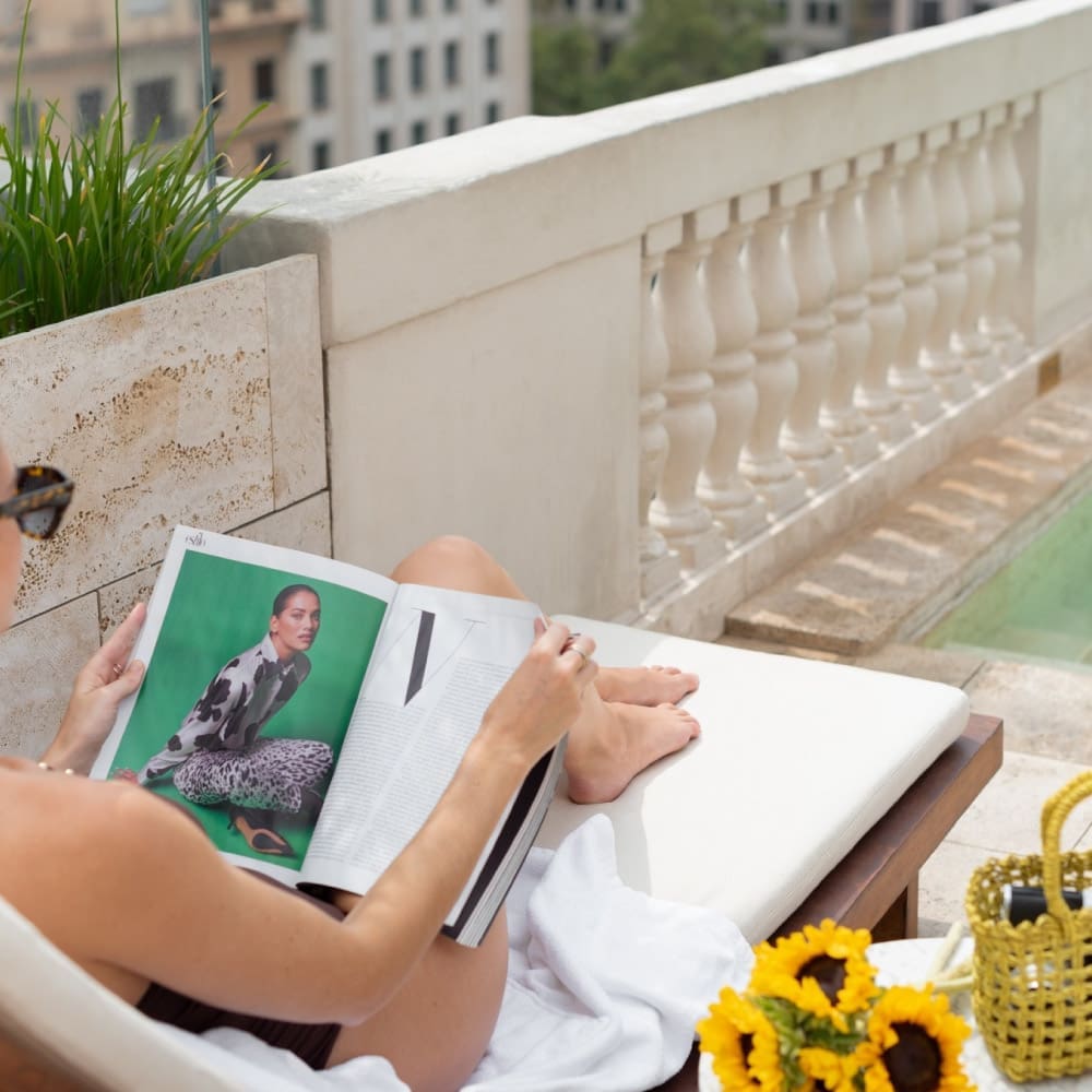 Sunlit afternoons unfold on the rooftop terrace, where classical balustrades frame city views and glossy magazines pair perfectly with golden sunflowers.