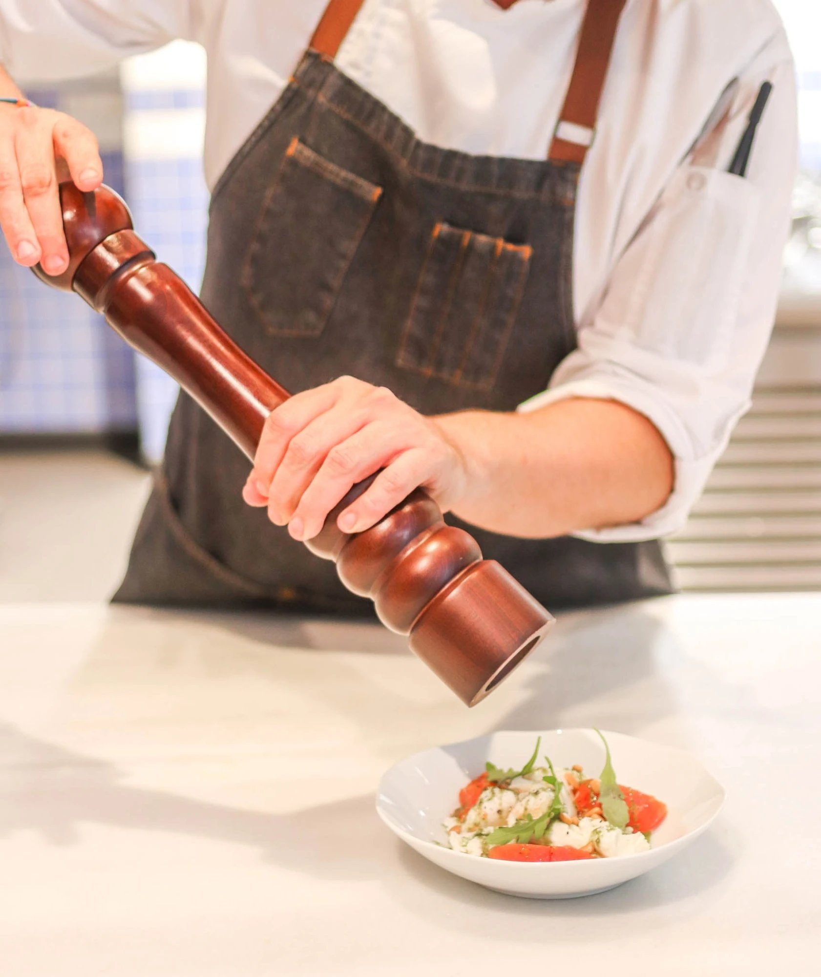 Fresh herbs and cracked pepper elevate each dish as skilled hands craft Mediterranean flavors in Seventy Barcelona's open kitchen, where culinary artistry meets warm hospitality.