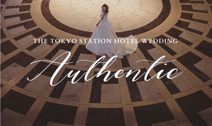 Marble floors radiate in geometric perfection beneath soaring ceilings, where a bride's silhouette creates an intimate moment within Tokyo Station Hotel's grand architectural embrace.