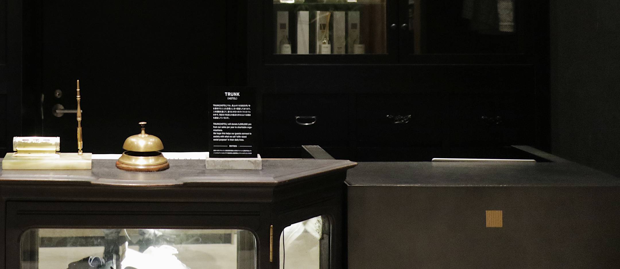 Brass service bells and minimalist amenities rest on sleek countertops, embodying TRUNK's thoughtful blend of traditional hospitality and contemporary Japanese design sensibilities.
