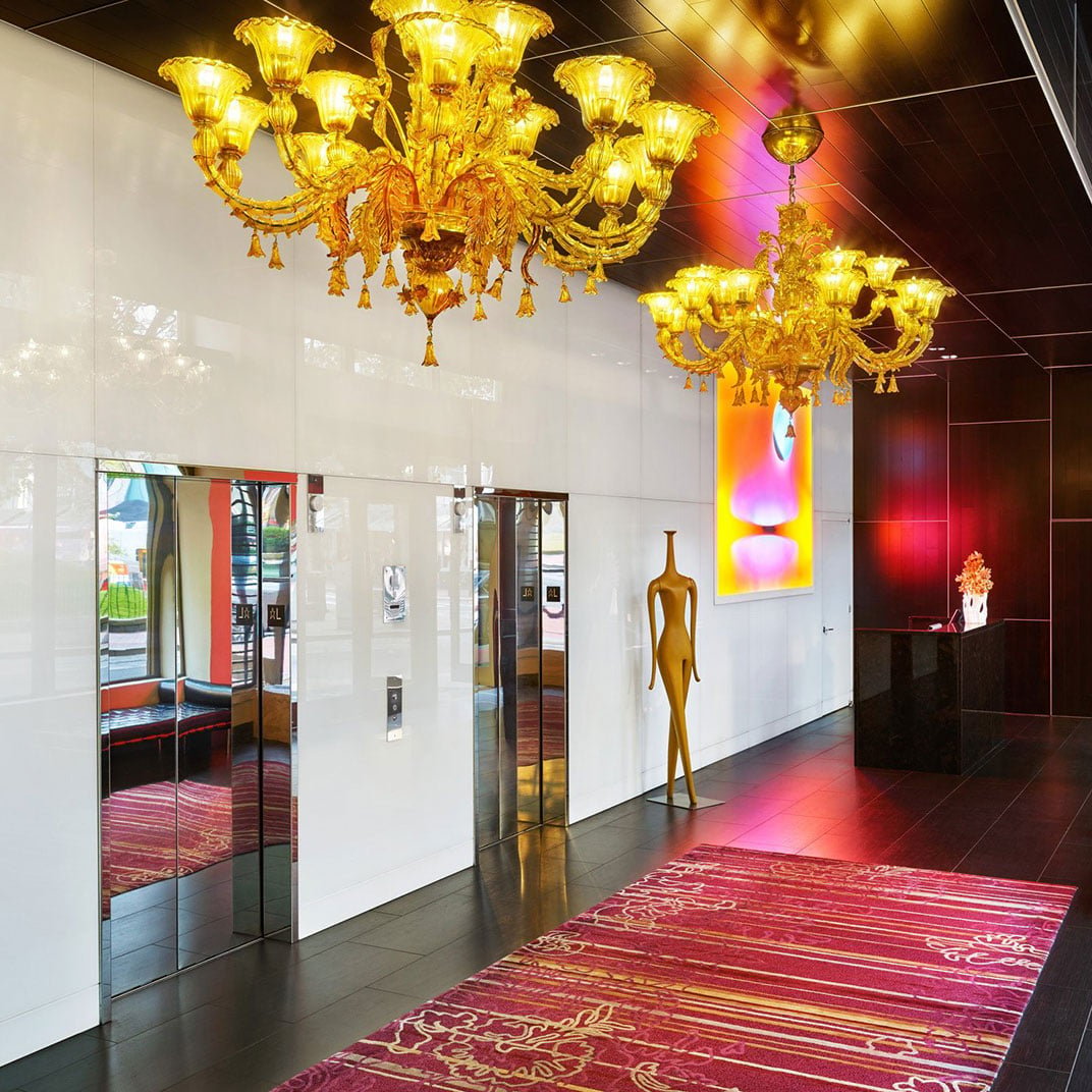 Golden Venetian chandeliers cast warm light across polished floors, where contemporary art meets burgundy Persian rugs in this sophisticated downtown Portland sanctuary.