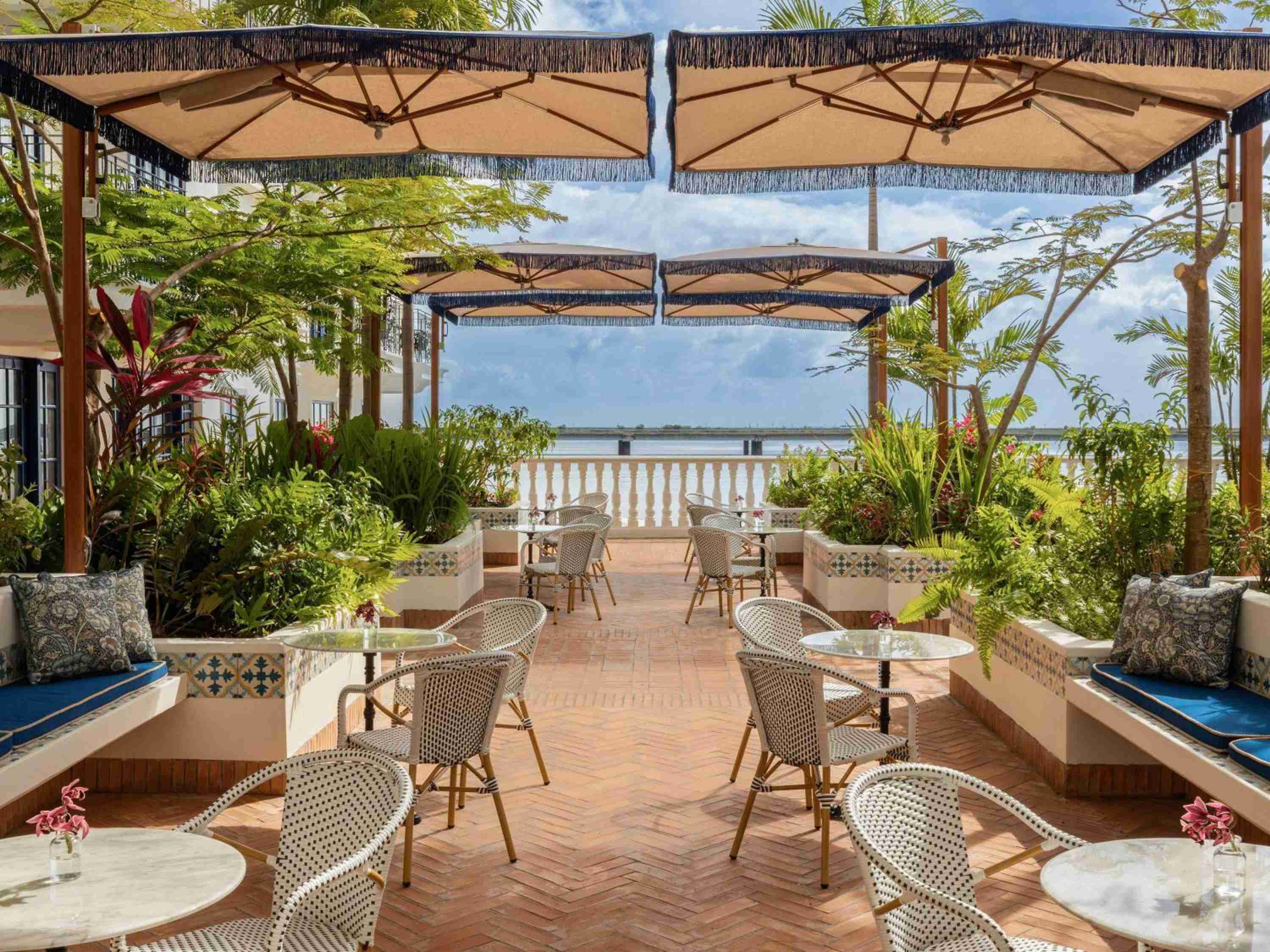 Wicker chairs and terra cotta tiles create an inviting terrace dining scene, where tropical umbrellas frame glimpses of Panama Bay's shimmering waters beyond.
