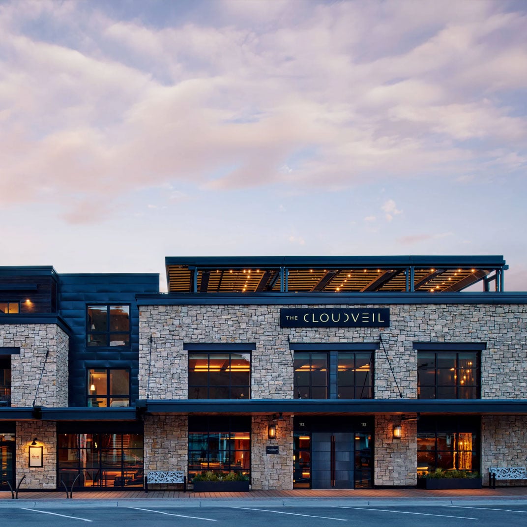 Stone and steel merge seamlessly as warm light spills from floor-to-ceiling windows, creating an inviting mountain sanctuary where modern architecture meets Jackson Hole's rugged spirit.