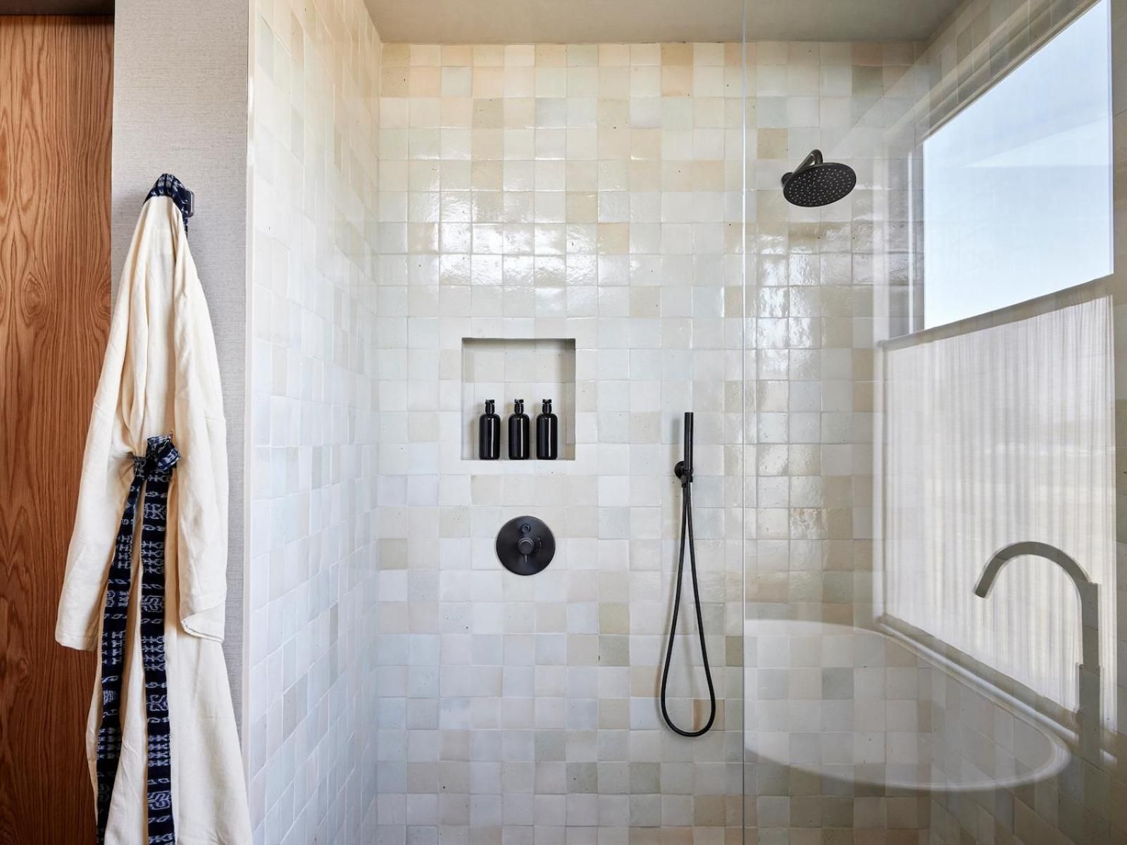 Handcrafted zellige tiles shimmer in natural light while black fixtures and a built-in niche create sophisticated contrast in this spa-inspired sanctuary.