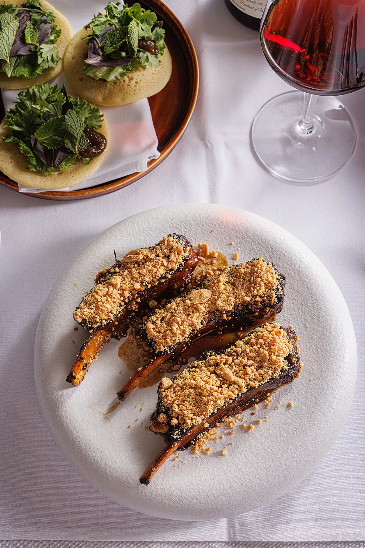 Charred lamb chops dusted with golden breadcrumbs arrive alongside herb-topped flatbreads, each dish crafted to complement the restaurant's carefully curated wine selection.