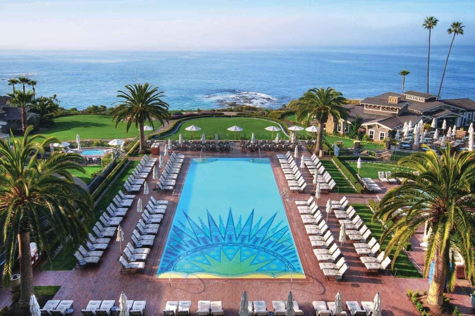 Palm-fringed perfection meets Pacific blues as Montage's mosaic-tiled pool stretches toward endless ocean horizons, white loungers beckoning beneath California's golden light.