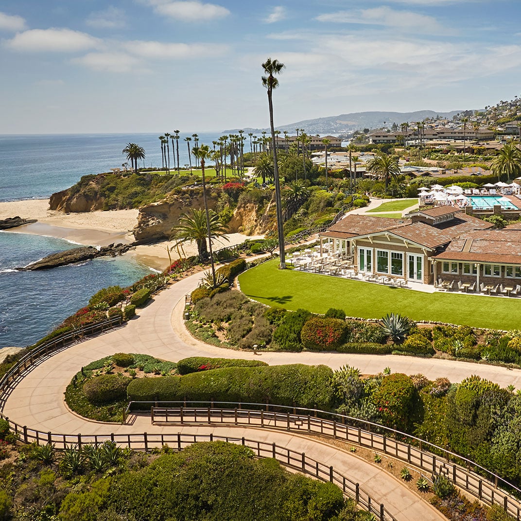 Dramatic clifftop perches reveal manicured lawns sweeping toward secluded sandy coves, where swaying palms frame the endless Pacific horizon beyond Laguna's sculptural coastline.