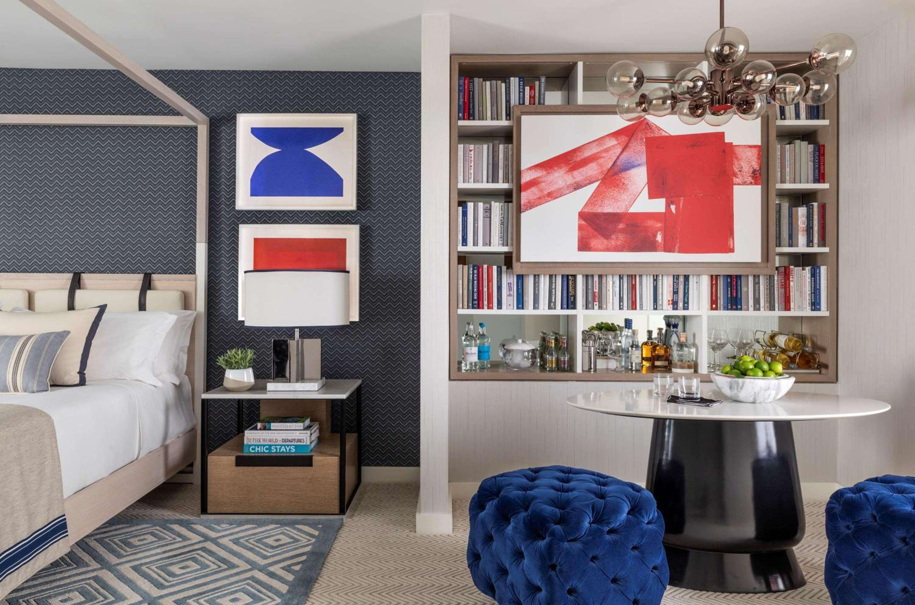 Bold geometric wallpaper and sapphire velvet ottomans create an artful retreat where contemporary design meets coastal sophistication in this thoughtfully curated suite.