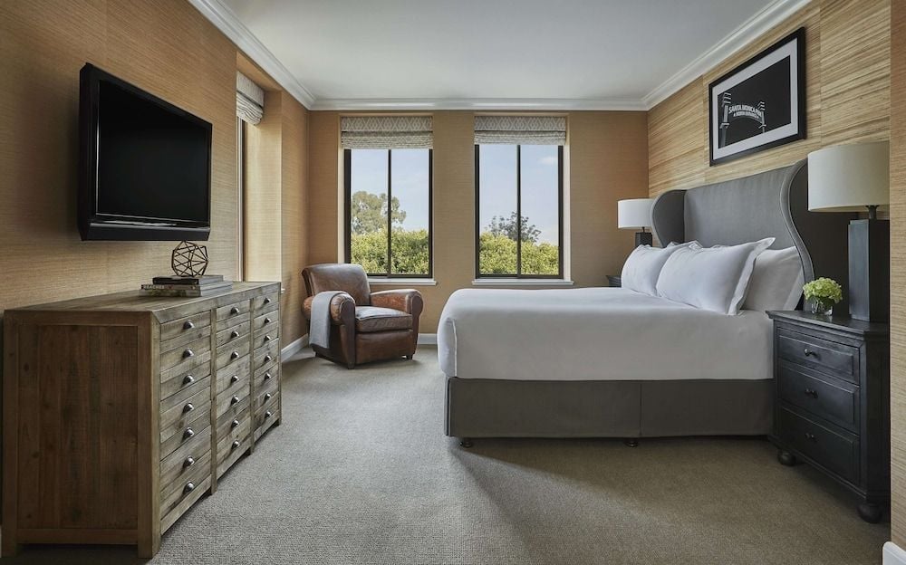 Warm grasscloth wallpaper and rich leather textures create an intimate sanctuary, where morning light filters through custom window treatments onto crisp white linens.