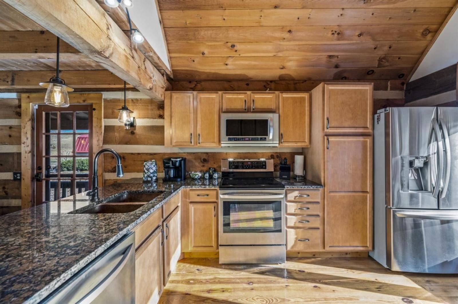 Rustic log beams frame a gourmet kitchen where granite countertops and stainless steel appliances blend seamlessly with hand-hewn timber, creating mountain luxury at its finest.