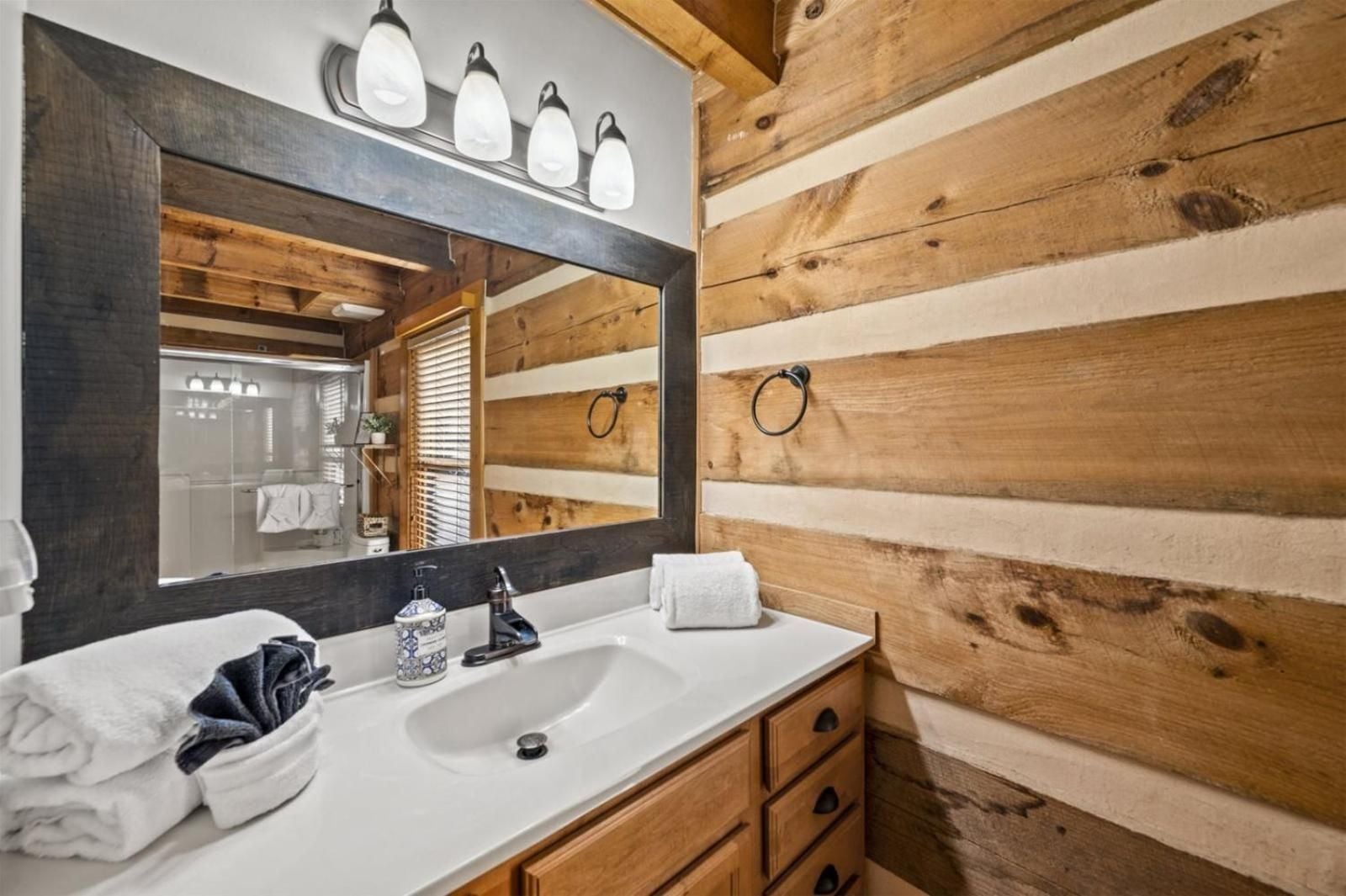 Reclaimed wood beams and rustic log walls create an intimate sanctuary where modern amenities blend seamlessly with Appalachian craftsmanship in this thoughtfully appointed guest bathroom.