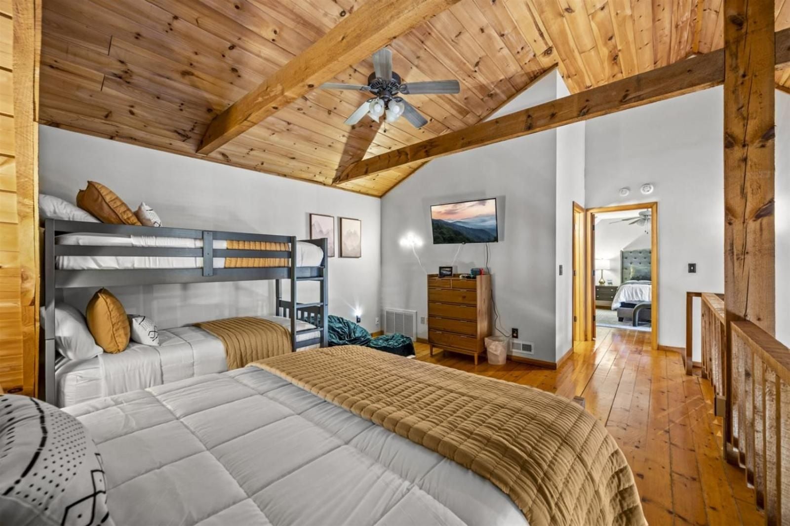 Exposed timber beams and cozy bunk beds create a sophisticated family retreat where rustic mountain charm meets thoughtful design in this inviting guest suite.