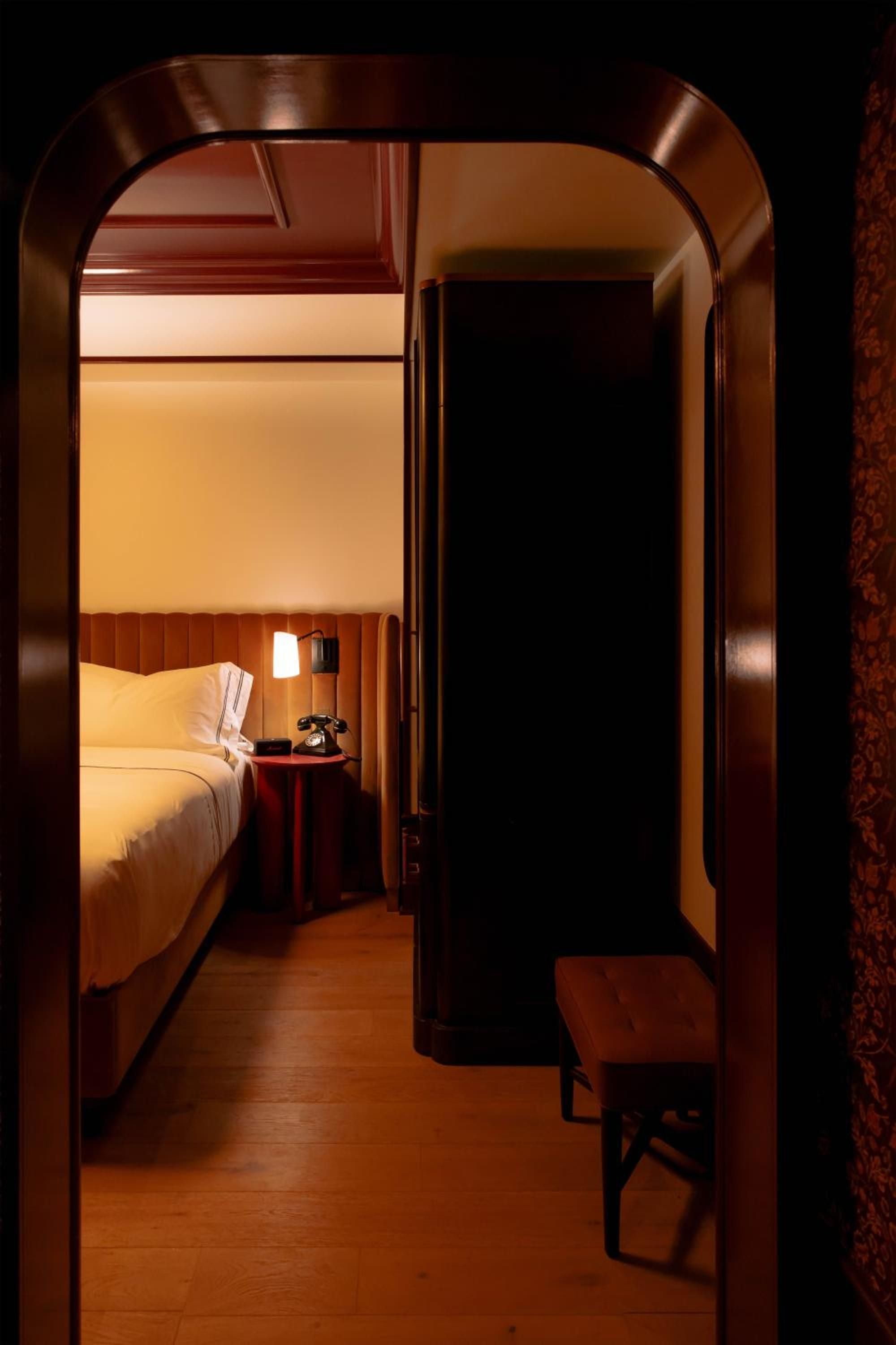 Burnished copper archways frame intimate sleeping quarters where warm wood paneling and soft amber lighting create a cocoon-like retreat from the world.